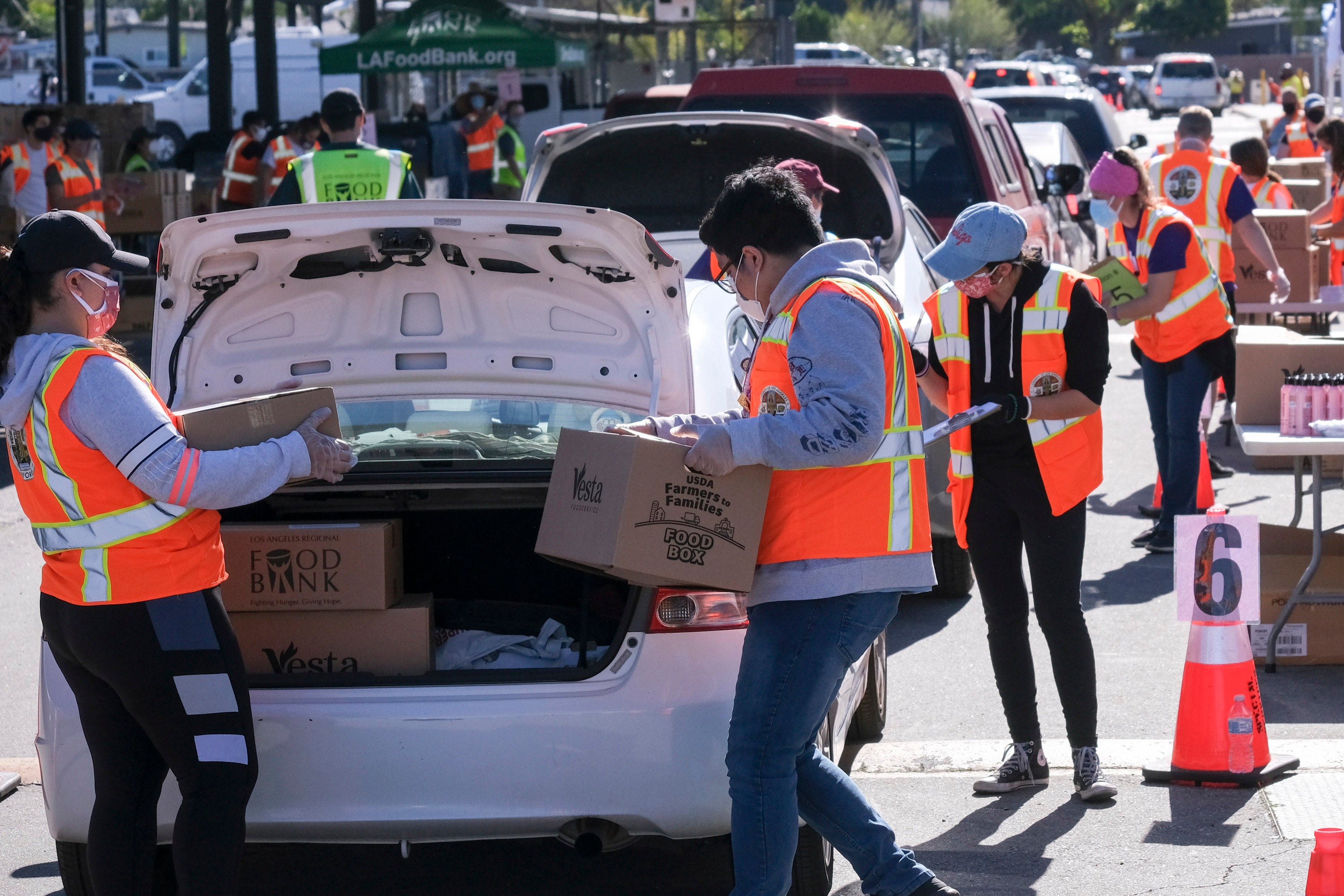 Volunteers load food into the trunk of vehicles during a ''Let's Feed LA County'' drive-thru food distribution by the Los Angeles Regional Food Bank and the office of Supervisor Hilda Solis on February 23, 2021, in La Puente, California.