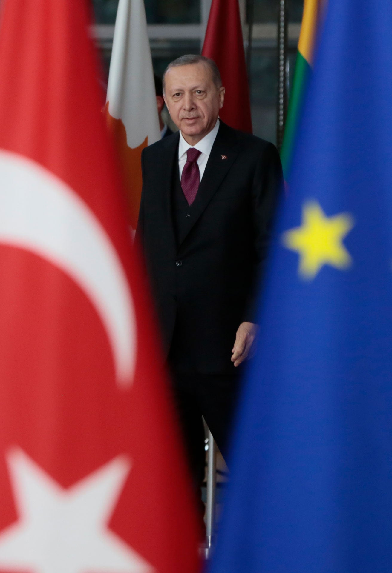 Turkish President Recep Tayyip Erdogan is seen walking near the Turkish and European Union flags.