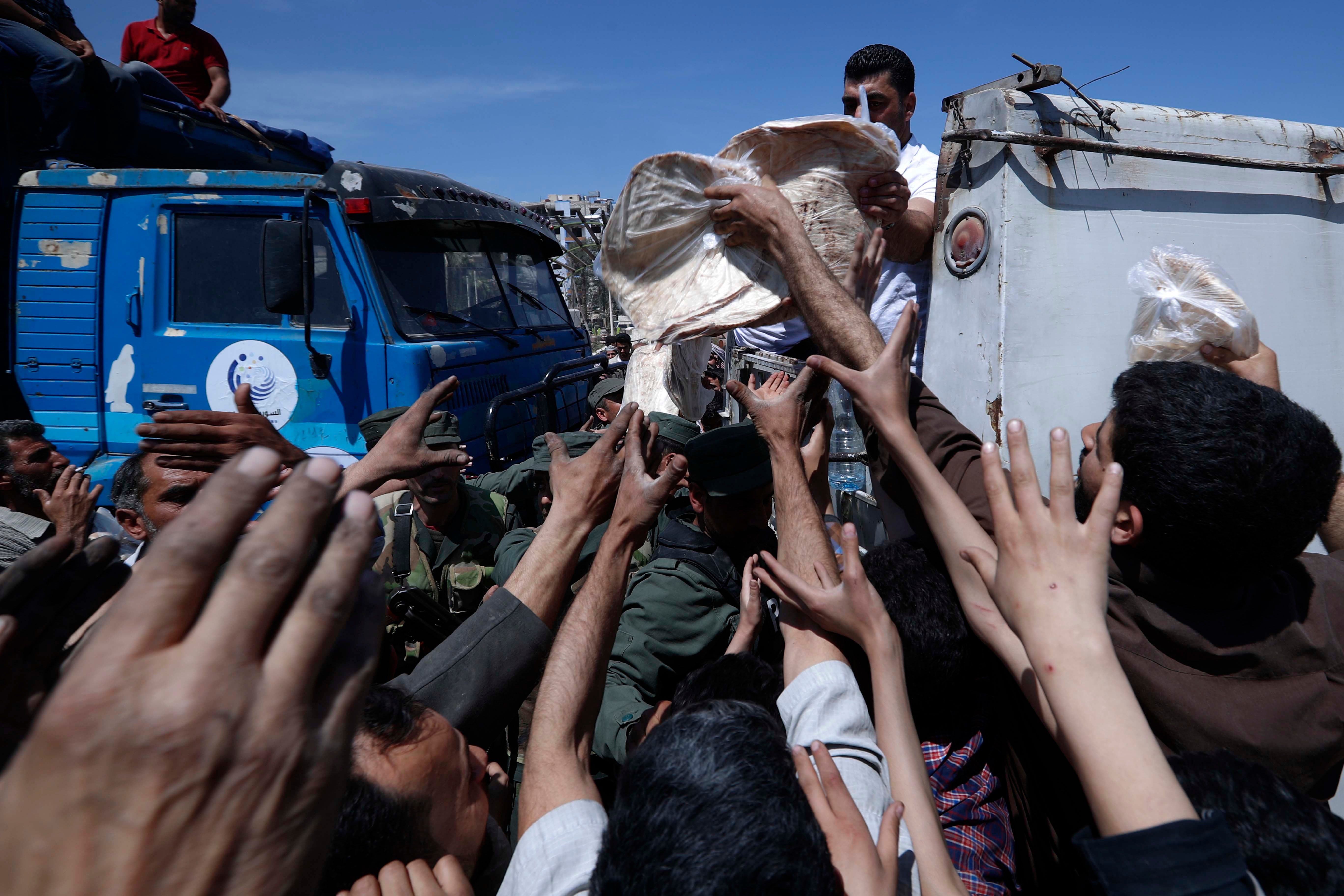 Des habitants de Douma, en Syrie, tendaient les bras lors de la distribution de nourriture effectuée dans cette ville le 16 avril 2018. 