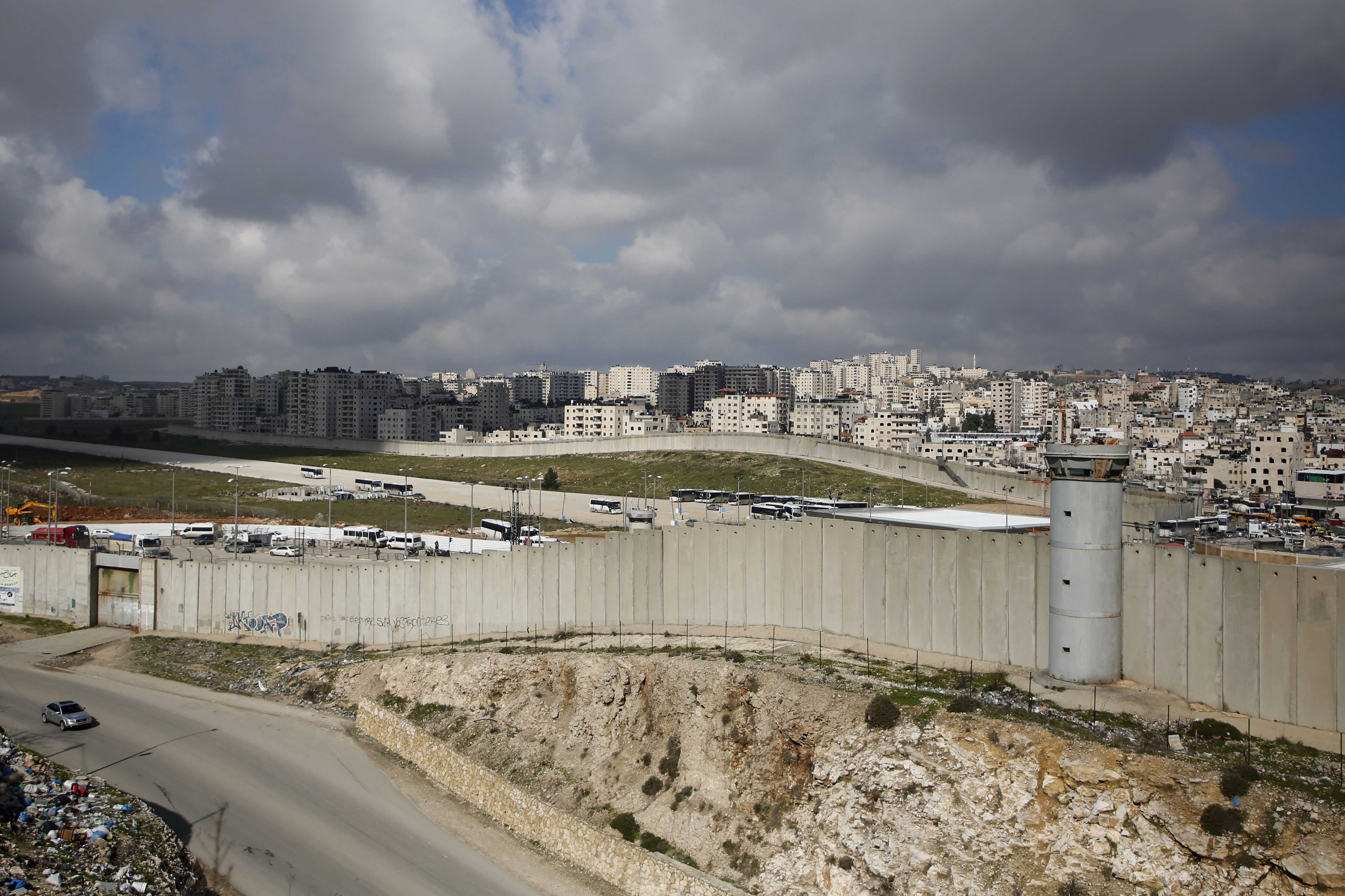 A concrete wall separates a city and a highway