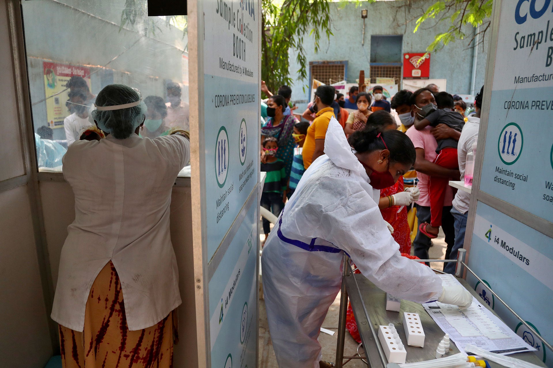 People wait to get tested for Covid-19 in Hyderabad, India. A crowd stands before two health care workers. 