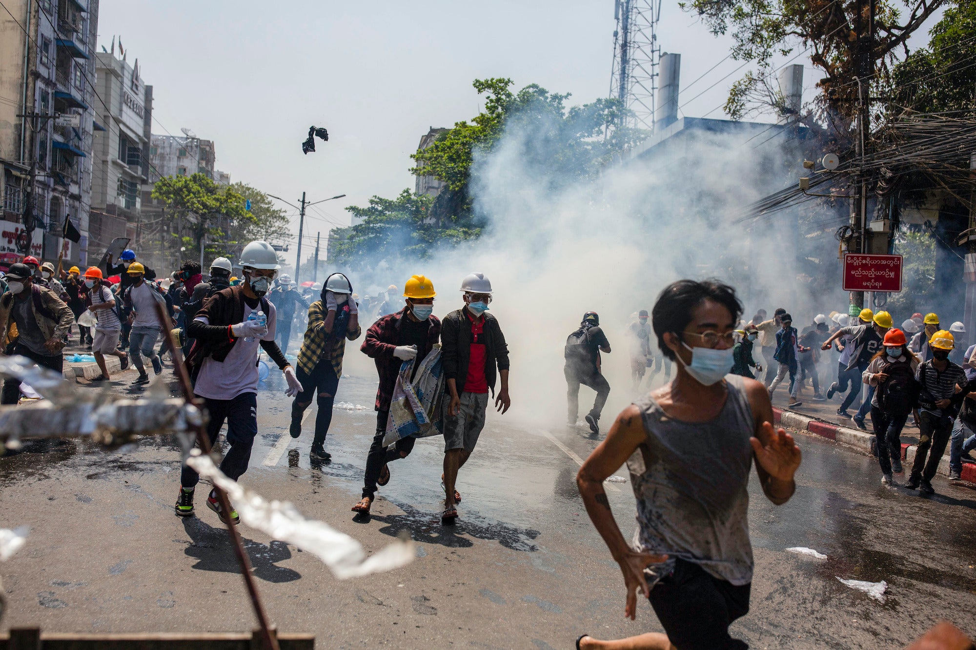 Des manifestants, dont un grand nombre portaient des casques jaunes et blancs, fuyaient sous des nuages de gaz lacrymogènes tirés par la police à Yangon, au Myanmar, le 1er mars 2021. Ces manifestants avaient tenté d’exprimer leur opposition au coup d'État militaire mené un mois auparavant, le 1er février 2021.