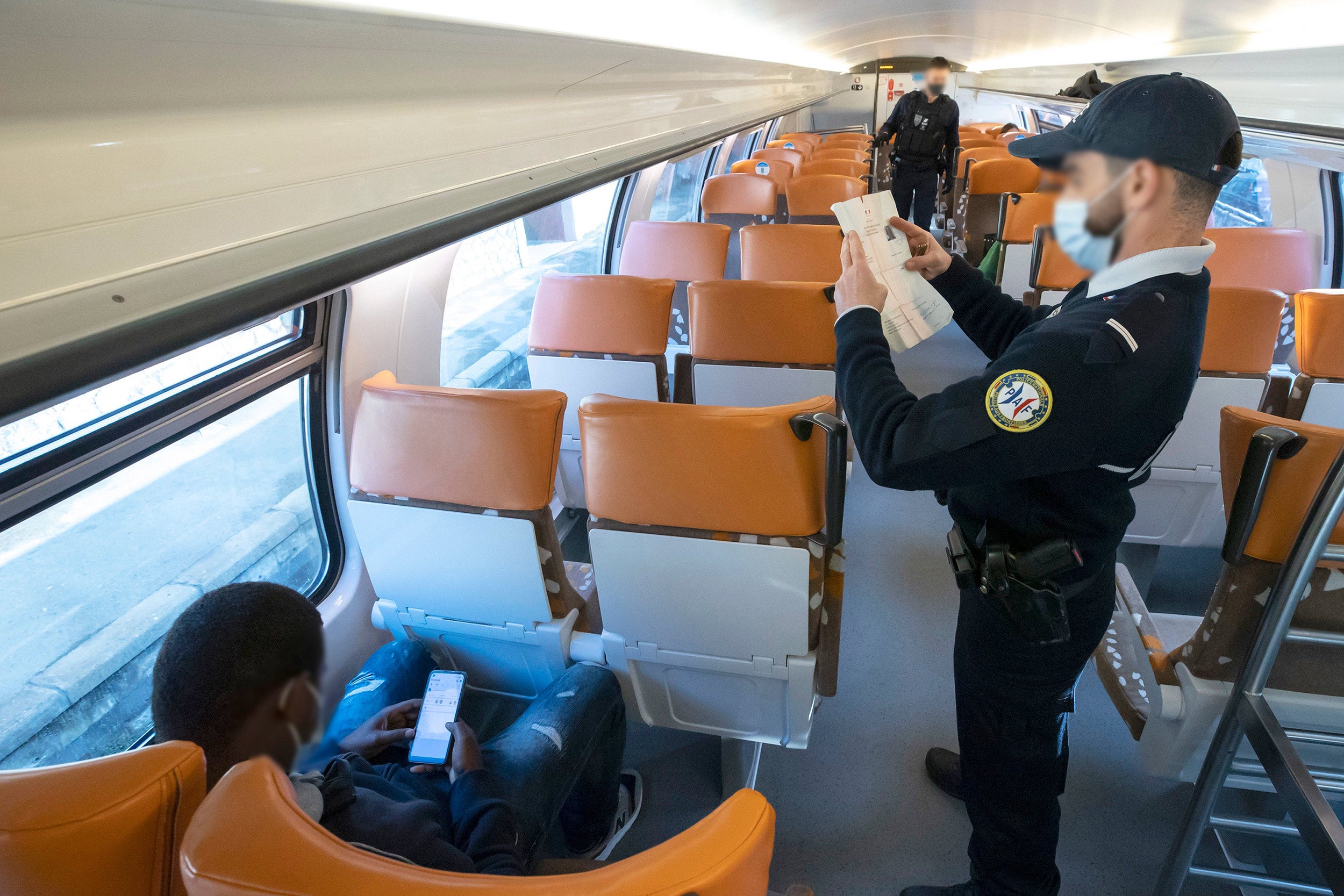 Un membro della polizia di frontiera francese controlla i documenti d'identità nel marzo 2021 alla stazione di Menton-Garavan, la prima stazione ferroviaria francese per chi viaggia tra Genova, in Italia, e Nizza, in Francia.