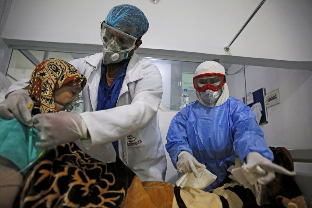 عاملان طبيان يعتنيان بمريض لديه فيروس "كورونا" في وحدة العناية المركّزة في أحد مستشفيات صنعاء، اليمن في 14 يونيو/حزيران 2020.