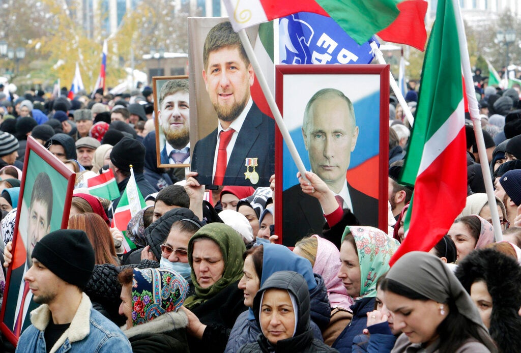 Люди держат портреты президента России Владимира Путина и главы Чечни Рамзана Кадырова во время митинга по случаю Дня народного единства в Грозном 4 ноября 2019 года.