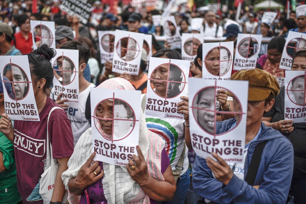 Protesters hold up pictures of victims of extrajudicial killings during Human Rights Day protests in Manila