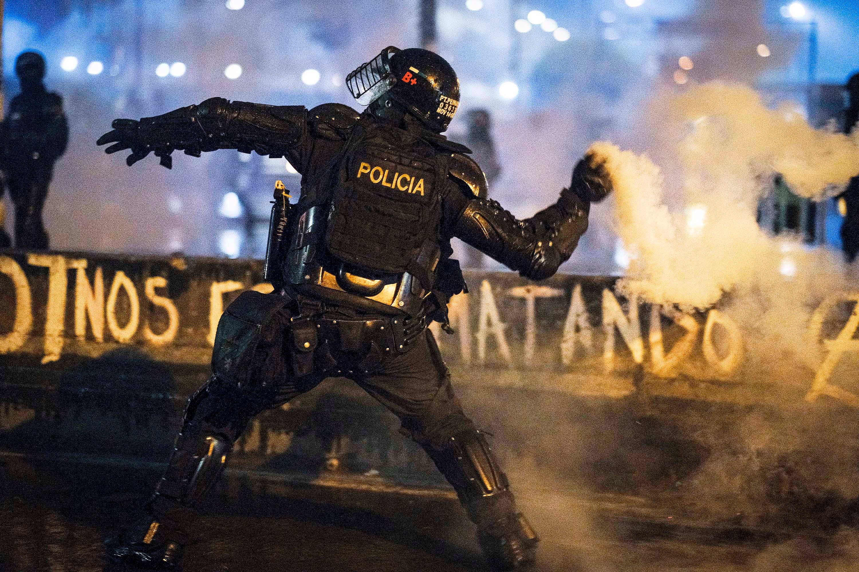 Um agente da ESMAD dispara uma bomba de gás lacrimogêneo manualmente contra os manifestantes em 28 de maio em Bogotá, Colômbia.