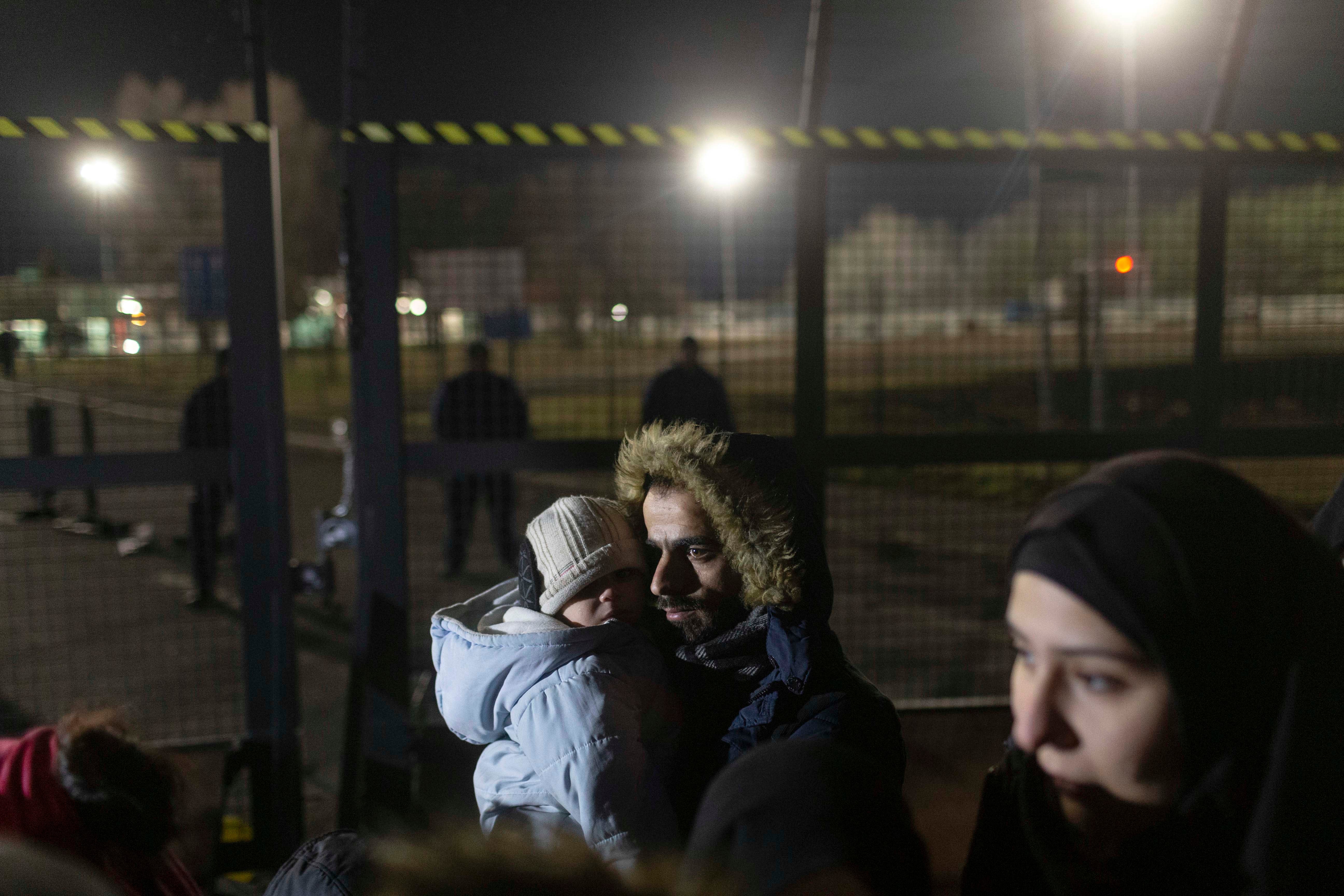 A man holds a child close to a border crossing between Serbia and Hungary, Kelebija, Serbia, Thursday, February 2020. 