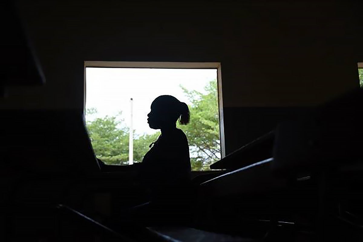 Une jeune femme se tient près d'une fenêtre dans un collège de Dakar.