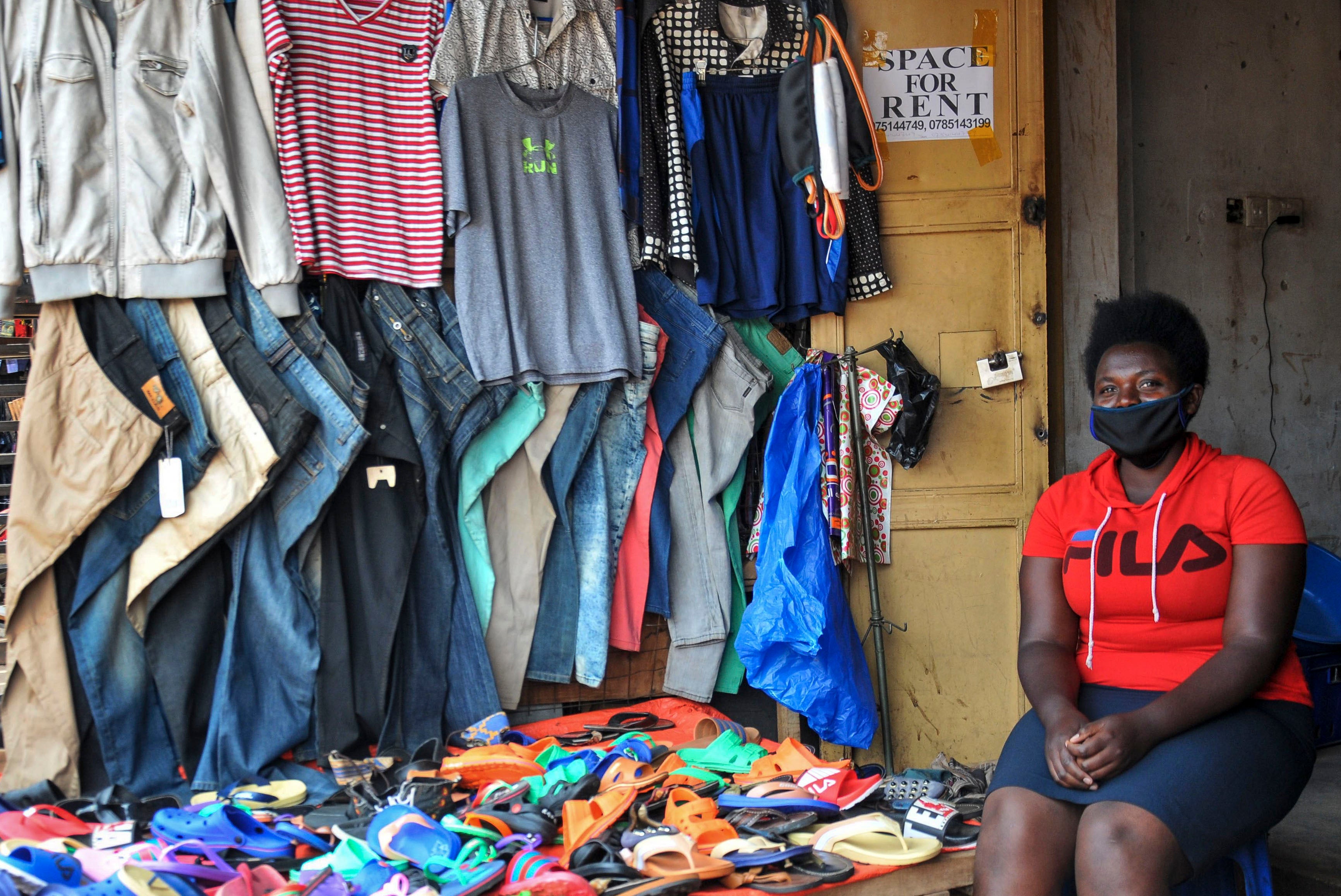 Grace Twisimire, 25, sits in her shop selling clothes and plastic shoes in Kampala, Uganda, June 20, 2020.
