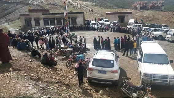 A large crowd standing in a circle outside of a monastery building