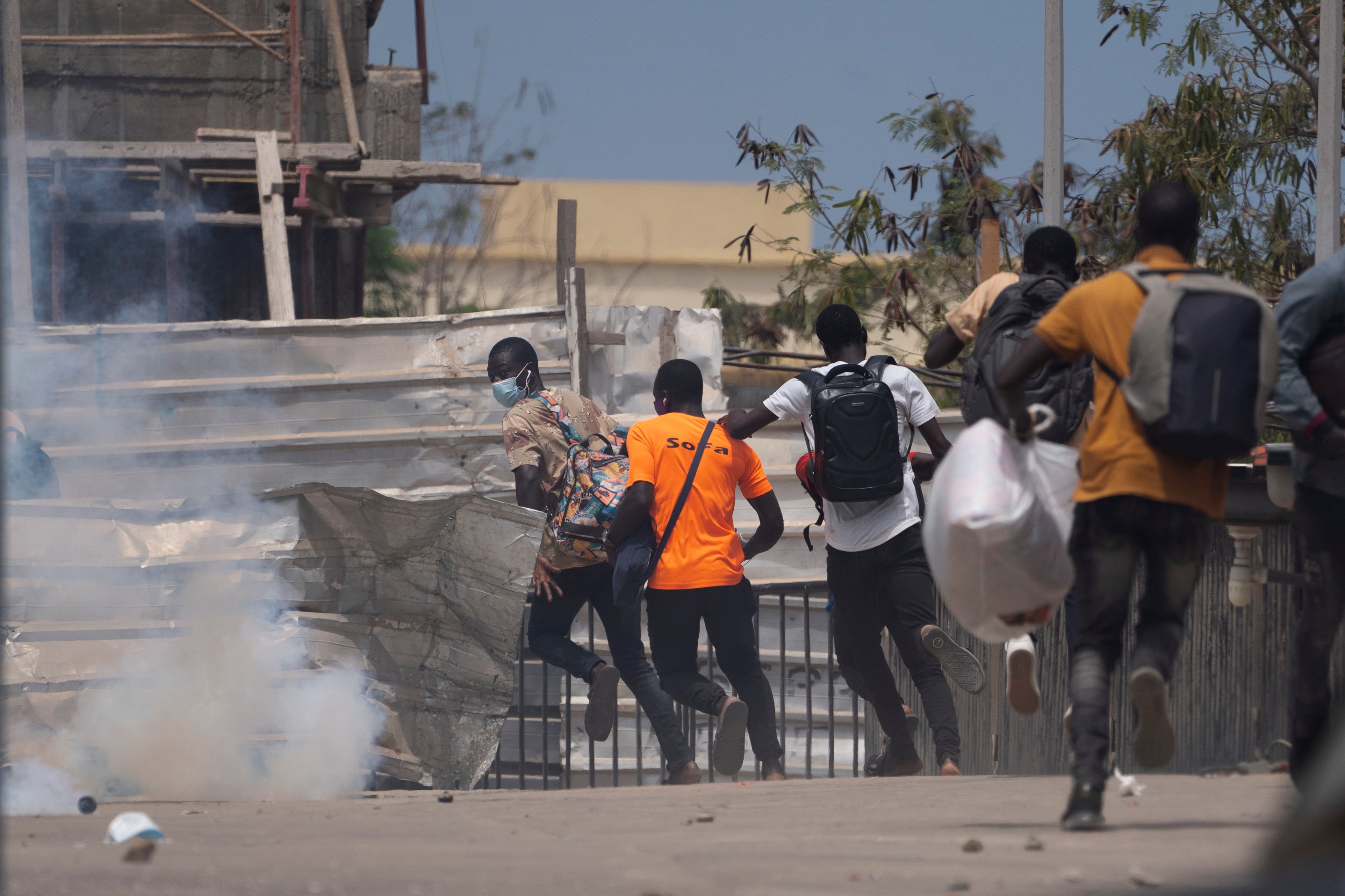 Des personnes fuient des gaz lacrymogènes tirés par la police anti-émeute lors d’une manifestation contre le projet de loi antiterroriste et une révision du Code pénal, tenue sur le campus de l’Université Cheikh Anta Diop à Dakar, au Sénégal, le 25 juin 2021. 