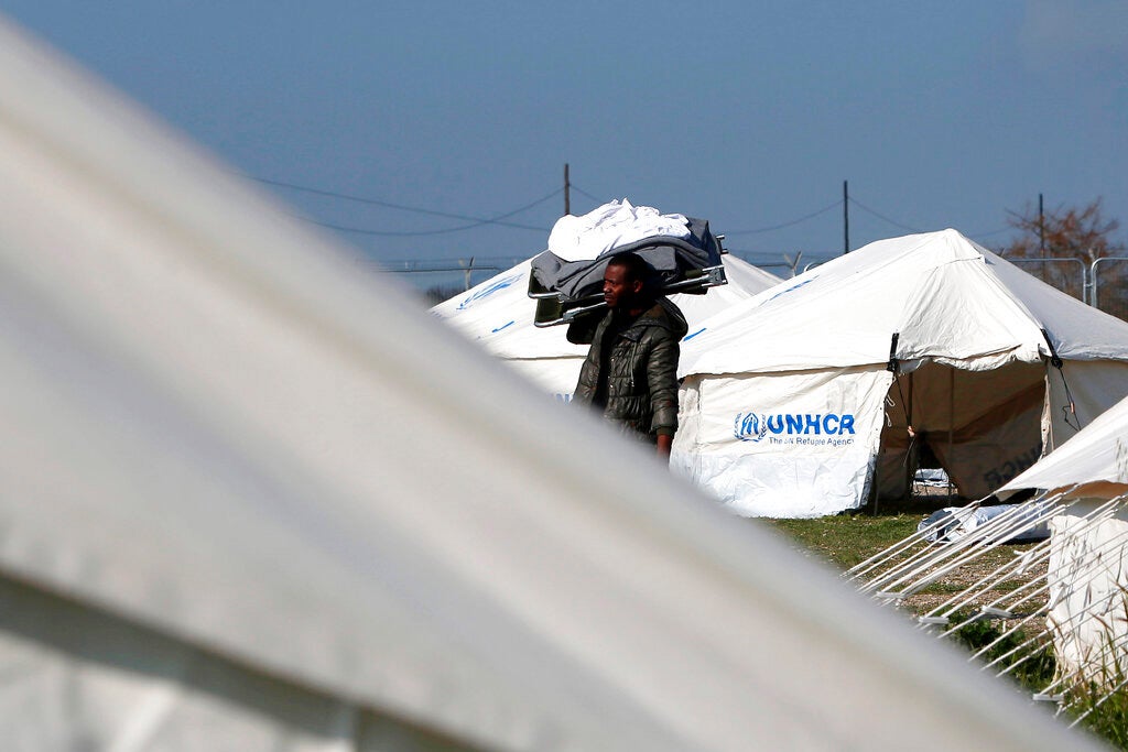 A migrant carrying a camp bed and bed clothes inside a refugee camp in Kokkinotrimithia outside of Nicosia, Cyprus, Tuesday, March 3, 2020.