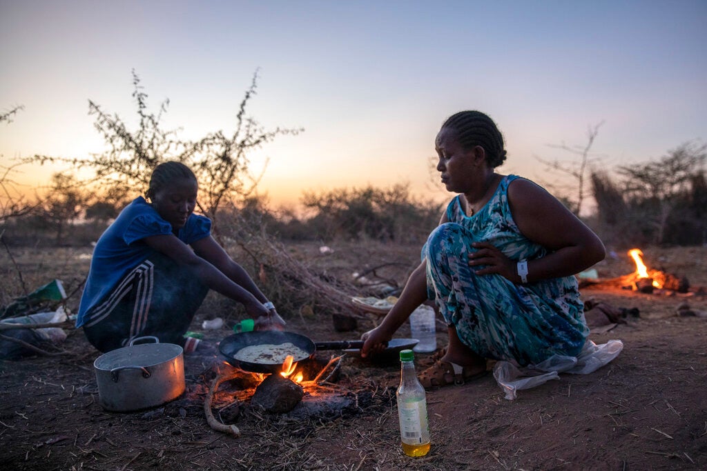 Deux femmes tigréennes ayant fui le conflit dans la région du Tigré, en Éthiopie, réchauffaient de la nourriture dans le camp de réfugiés d'Umm Rakouba à Qadarif, dans l'est du Soudan, le 25 novembre 2020. 