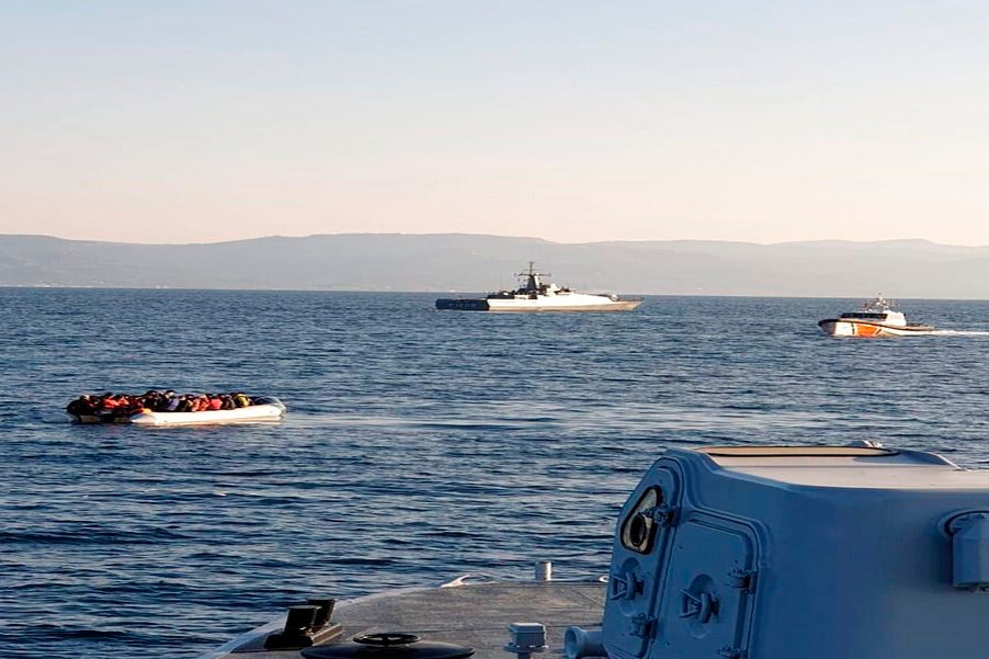 A dinghy with migrants, left, with Turkish ships in the background, in the narrow stretch of water between the eastern Greek island of Lesbos and the Turkish coast on April 2, 2021.