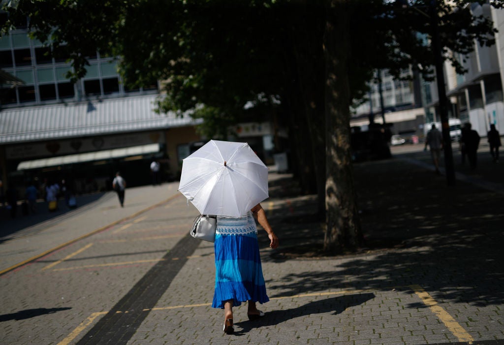 A woman walks under a parasol to shelter from the sun in Birmingham, U.K., on Tuesday, July 20, 2021. The U.K.'s Met Office has issued its first-ever Extreme Heat weather warning, stating that continuing high temperatures will lead to public health impacts.