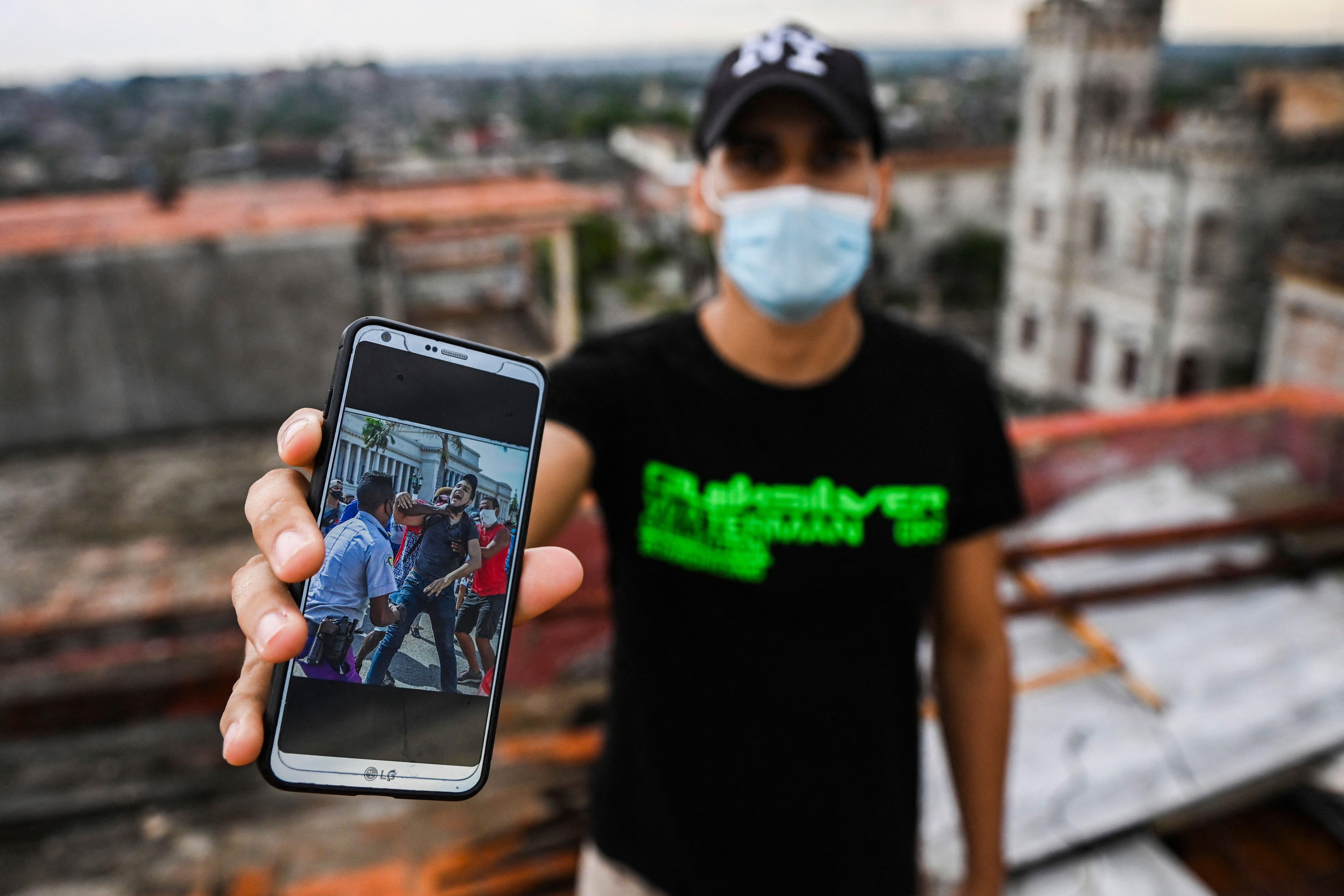 Cuban Rolando Remedios shows a photo of him being arrested during the July 11 protests on his mobile phone at his home in Havana, Cuba, on August 7, 2021.