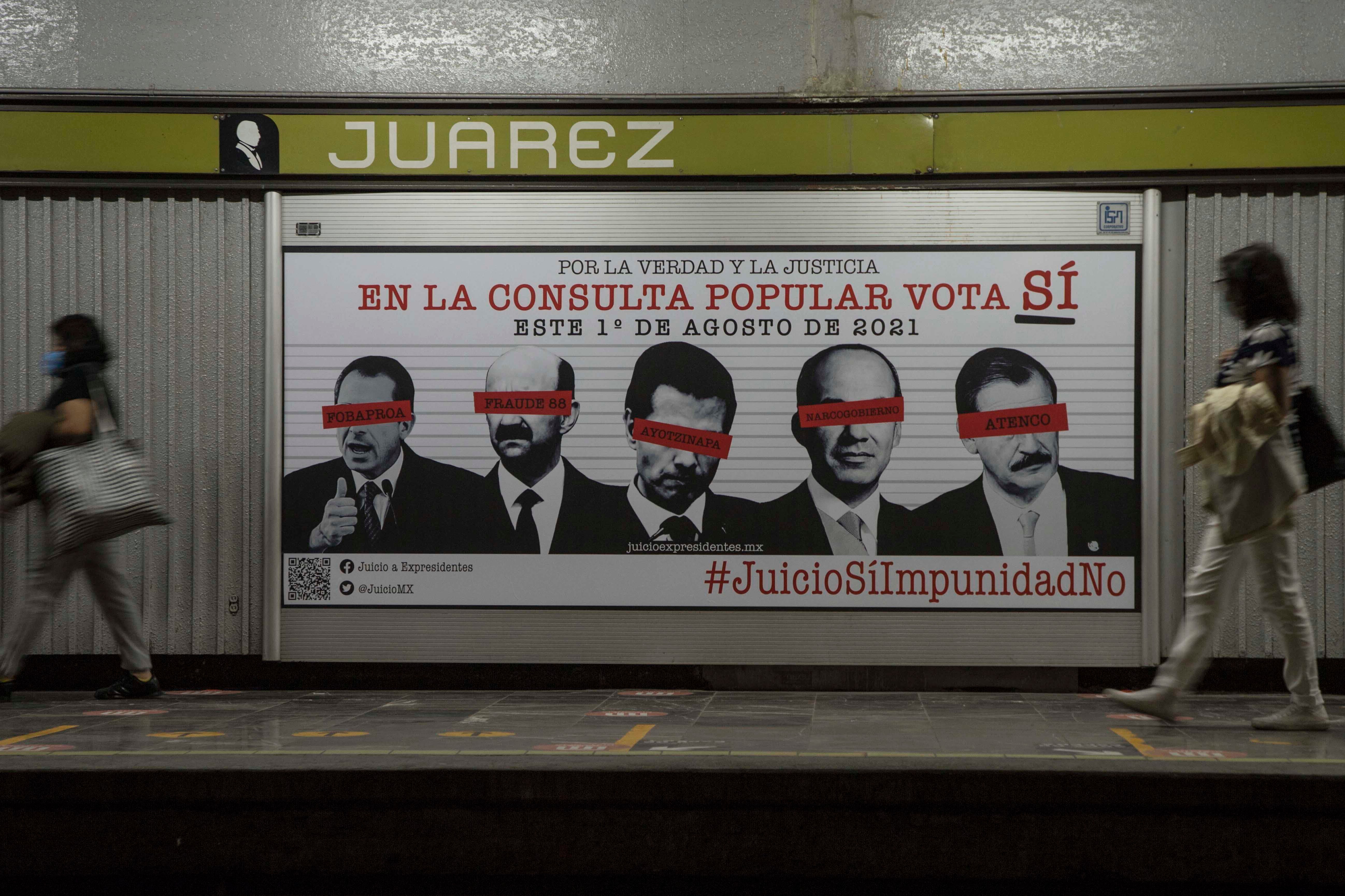 Commuters walk past an advertisement showing images of several former Mexican presidents, calling for citizens to participate in a referendum on whether ex-presidents should be tried for their alleged crimes during their time in office, in Mexico City, Saturday, July 31, 2021.