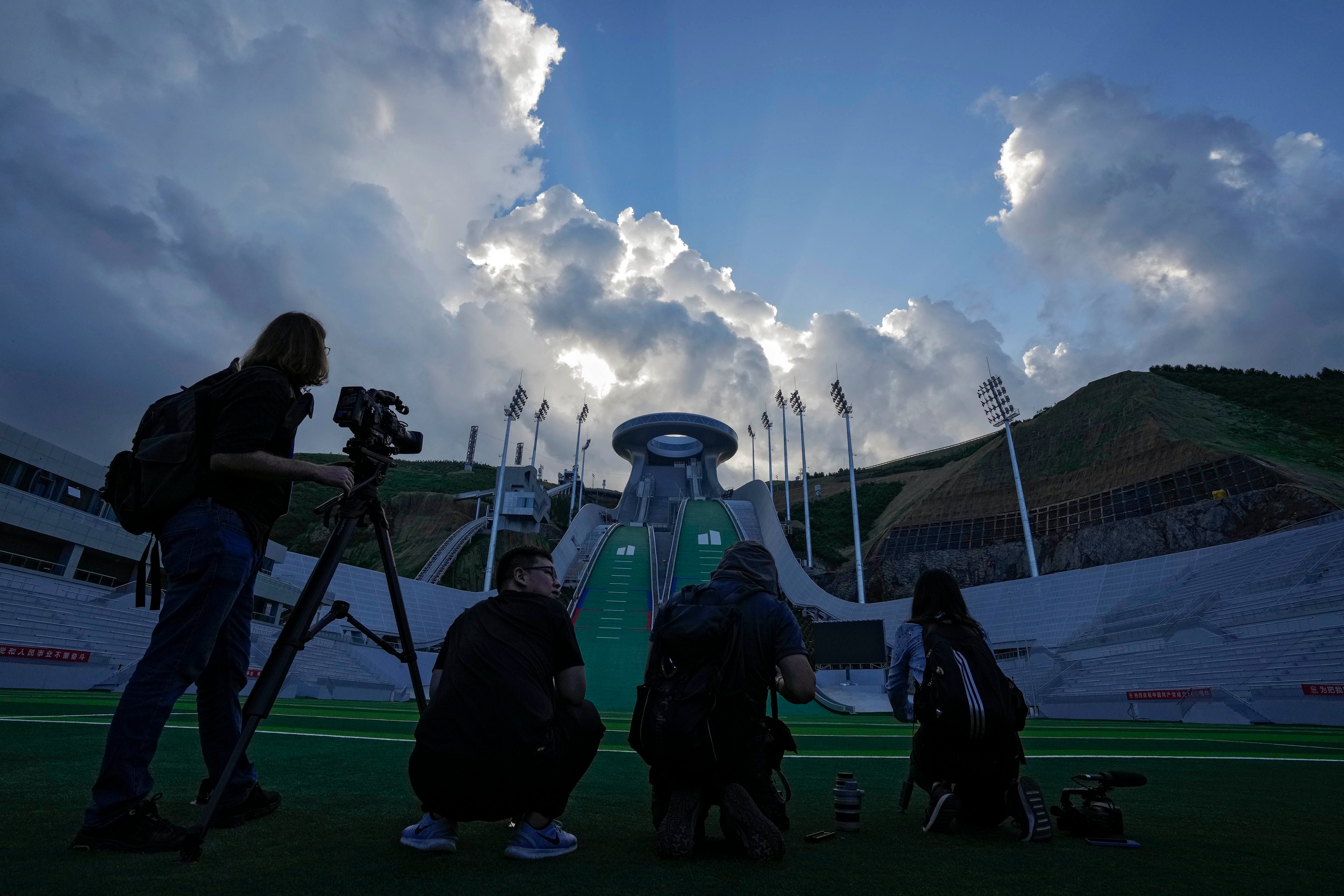 People with camera equipment standing in front of a venue for ski jumping