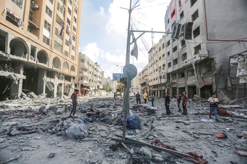 אנשים בעזה עומדים בתוך שברי בניין ברחוב אל-ג'לאא, בסמוך למגדל אל-ג'ווהרה שניזוק קשות בהתקפה אווירית ישראלית ב-12 במאי שהסבה נזק כבד גם לסביבתו.