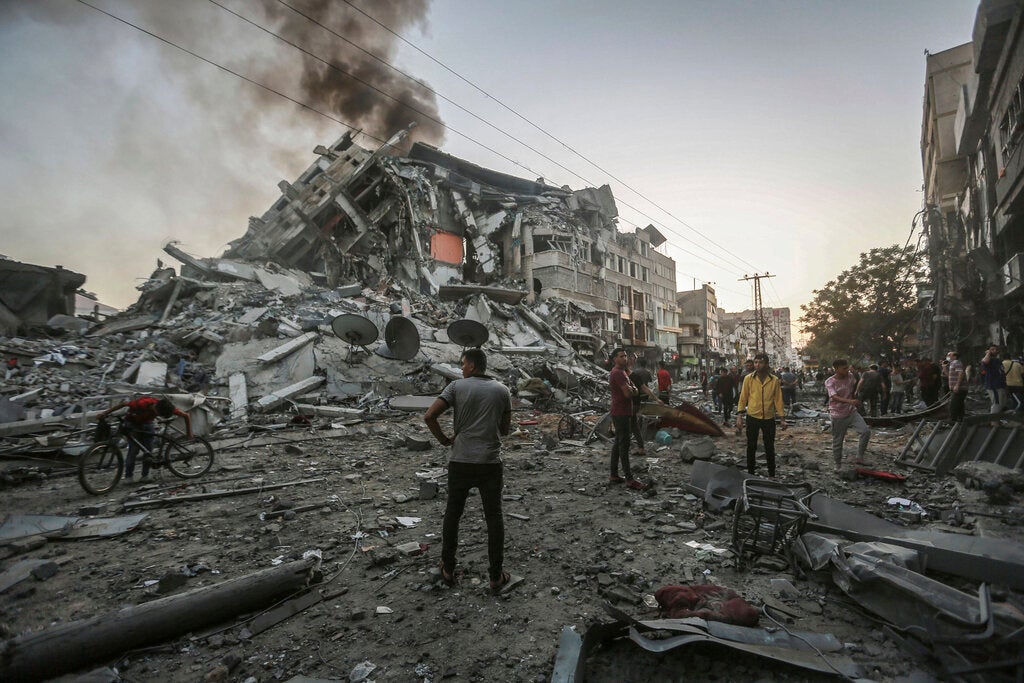 People in the Gaza Strip stand near the site of the collapsed al-Shorouk tower