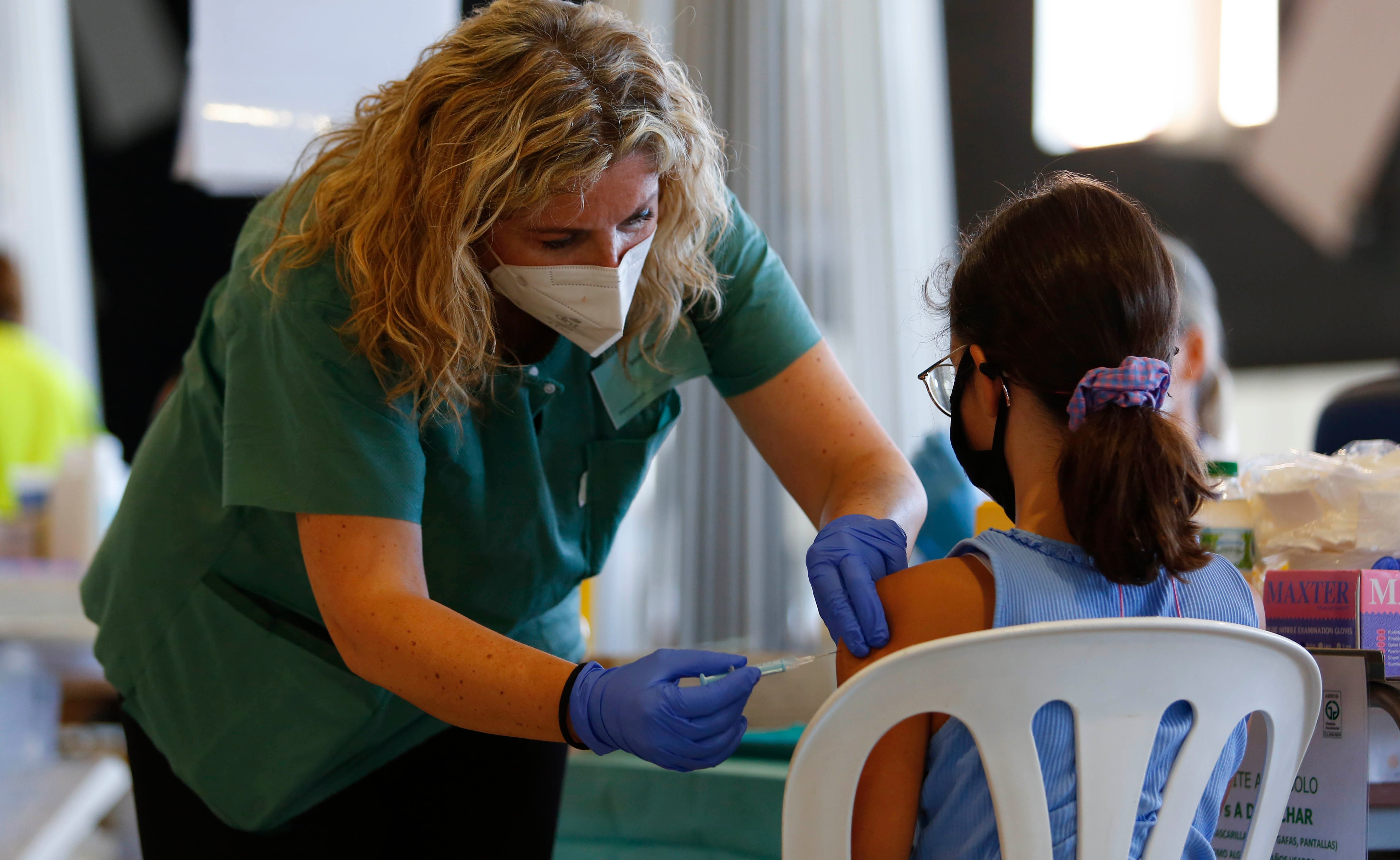 A nurse with a syringe explains and calms a girl while the COVID-19 vaccination goes on for children and young people in Granada, Spain on September 03, 2021. 