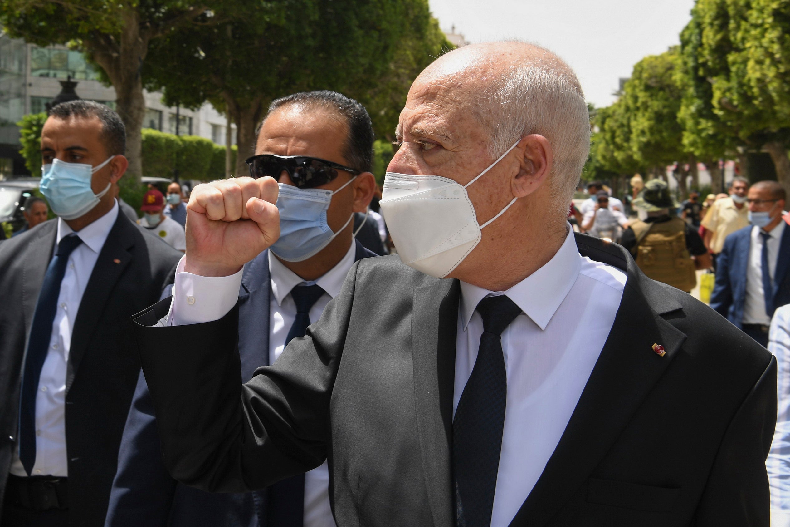 Le président tunisien Kaïs Saïed levait son poing en marchant sur l'avenue Bourguiba à Tunis, entouré de gardes du corps, le 1er août 2021. © 2021 Slim Abid/Présidence tunisienne via AP