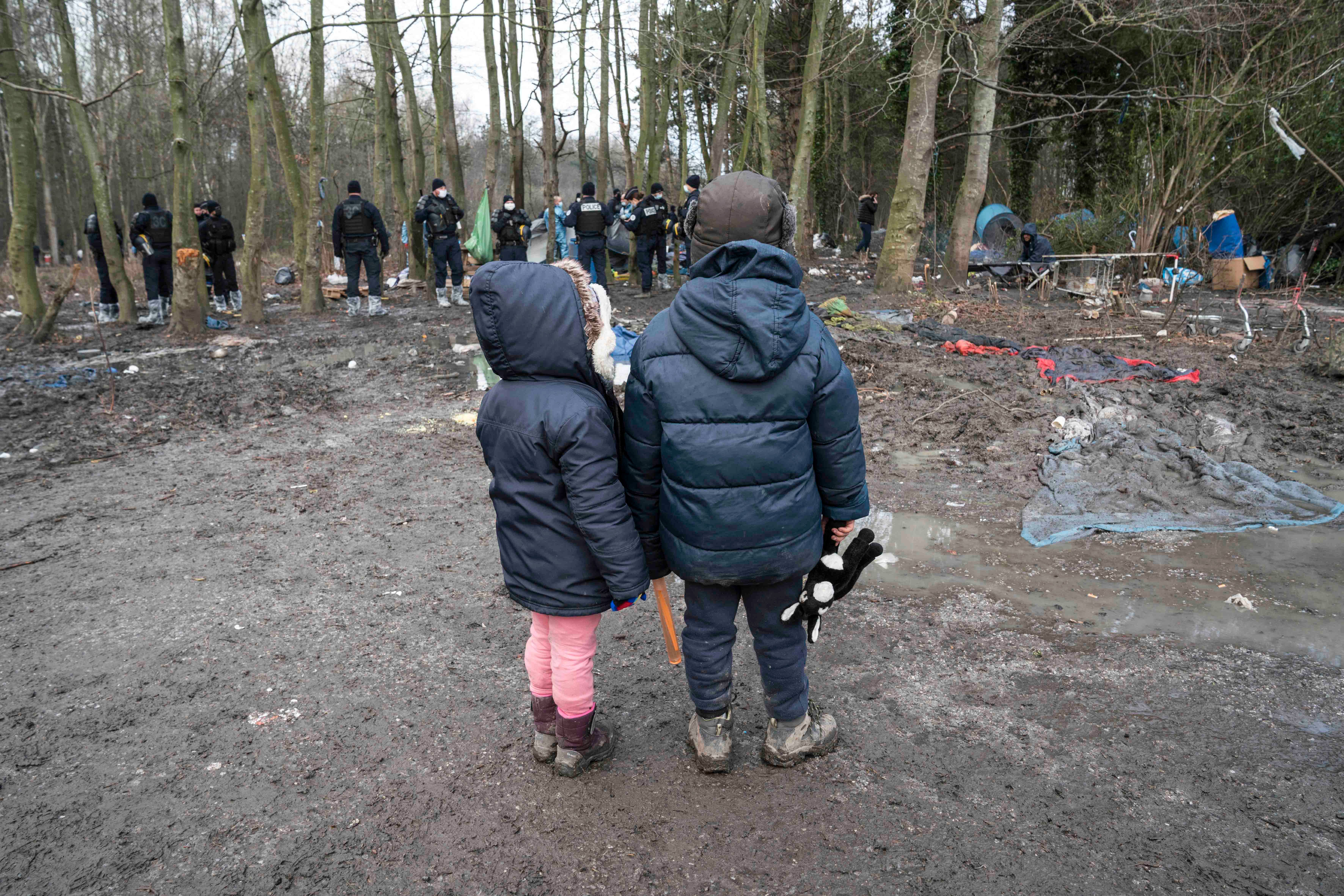 Zwei Kinder beobachten, wie die Polizei ihr Zelt bei der Räumung eines Migrantenlagers in Grande-Synthe, Nordfrankreich, am 21. Januar 2021 beschlagnahmt.