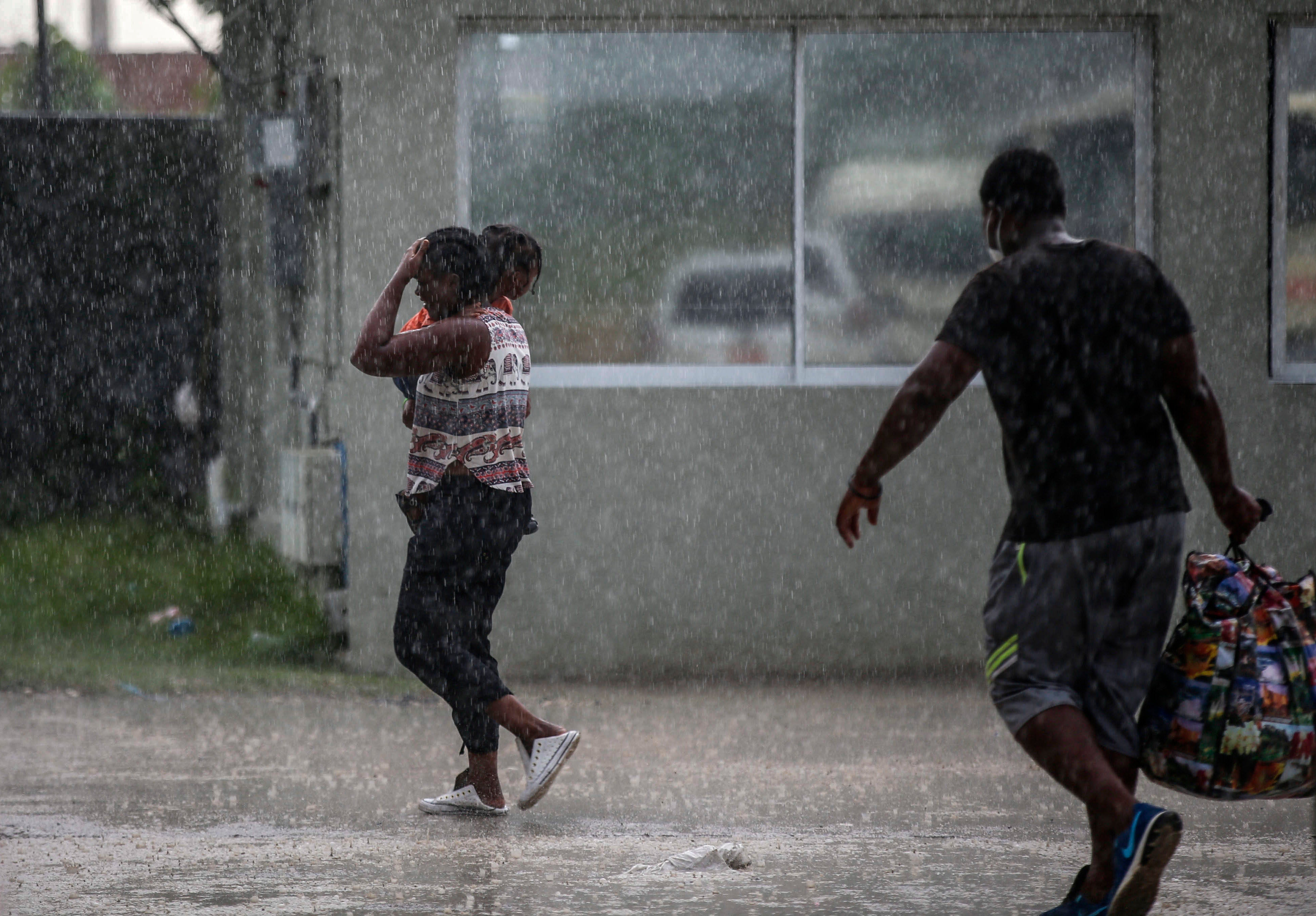 Haitians deported from the United States leave Toussaint Louverture International Airport under a rain shower in Port au Prince, Haiti on September 19, 2021.