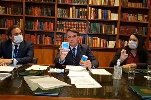 Brazil's President Jair Bolsonaro holds a drug he recommended to treat Covid-19 during a Facebook live event in April 2020. That drug has no proven effect against the virus.