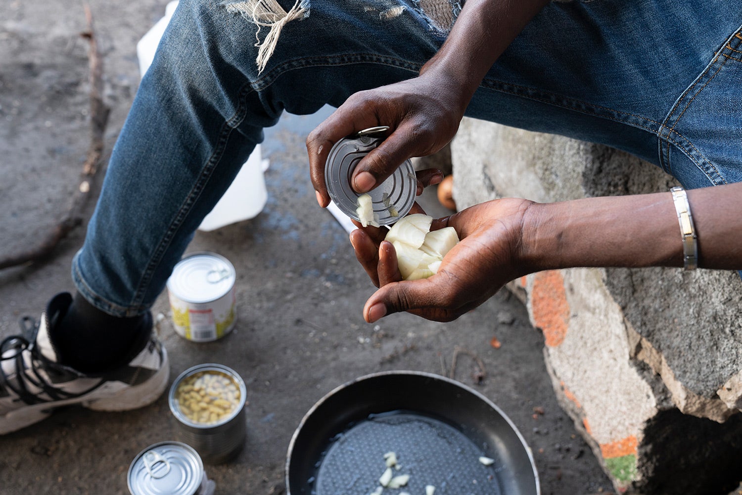 A 17-year-old Malian boy slices onions with the top of a metal can, July 2021, Calais, France.