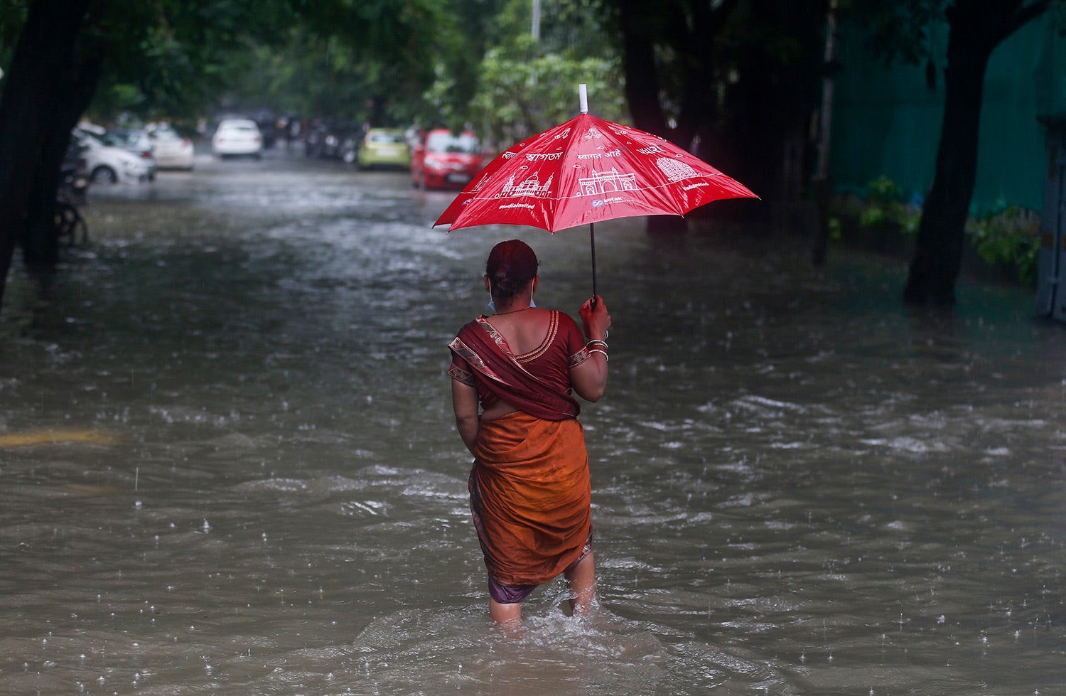 A woman walks through a flooded street during heavy rains in Mumbai, India on June 12, 2021.