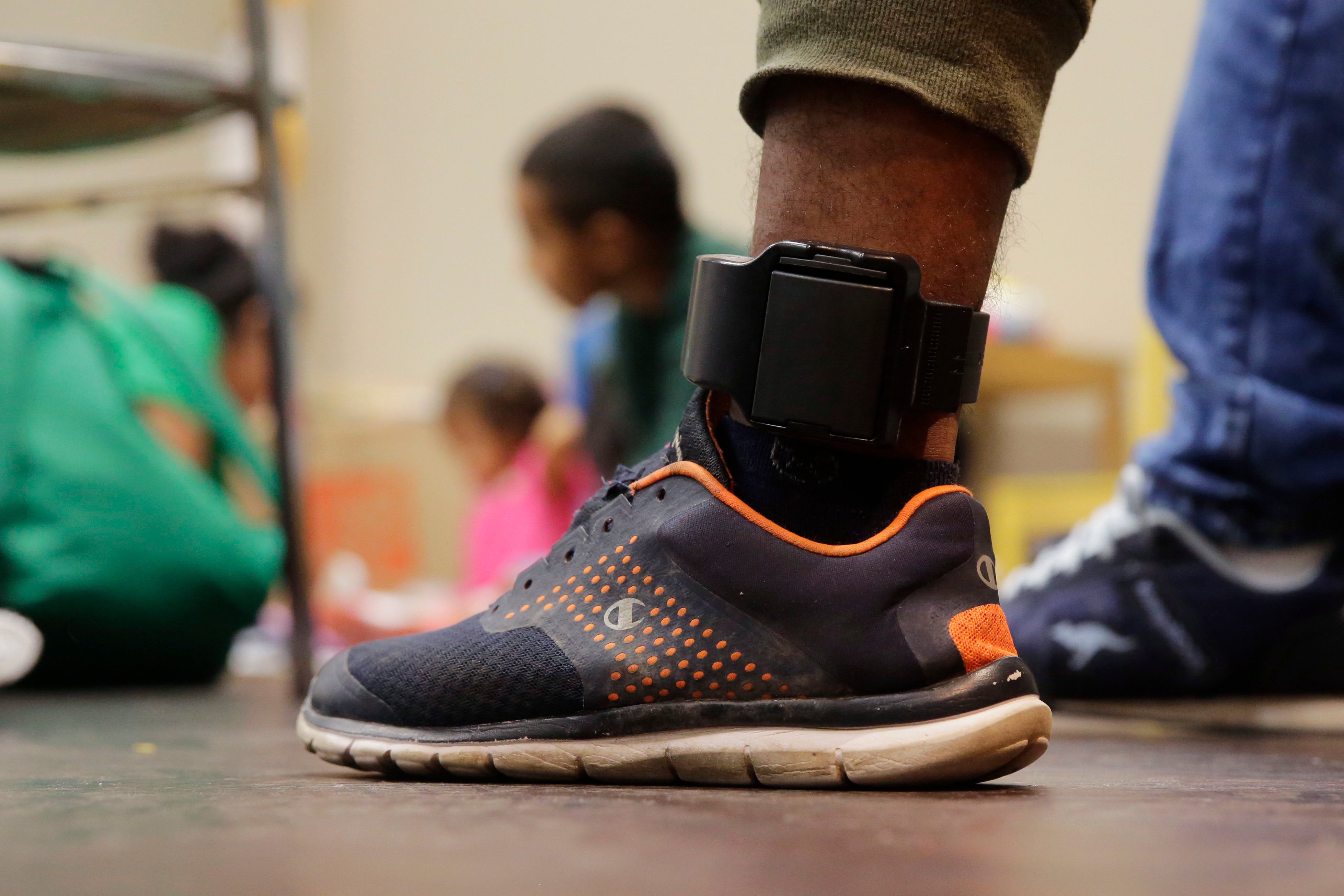 Close-up of a person wearing sneakers and an ankle monitor