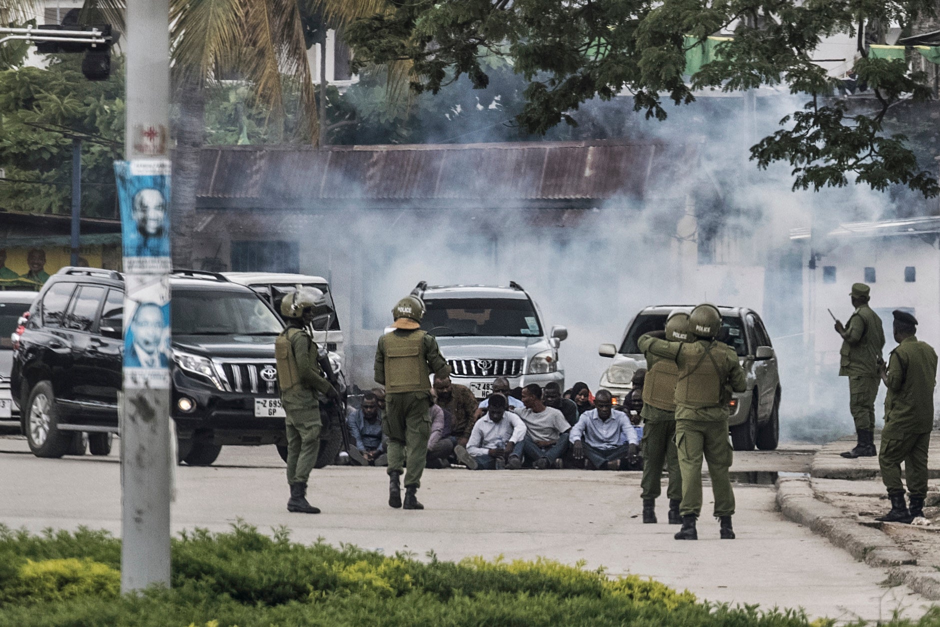 Zanzibar's anti-riot police officers stand guard by a group of men sitting on the ground during an operation after the opposition called for protests in Stone Town, on October 29, 2020 as tensions rise while the results of the general election are being announced.
