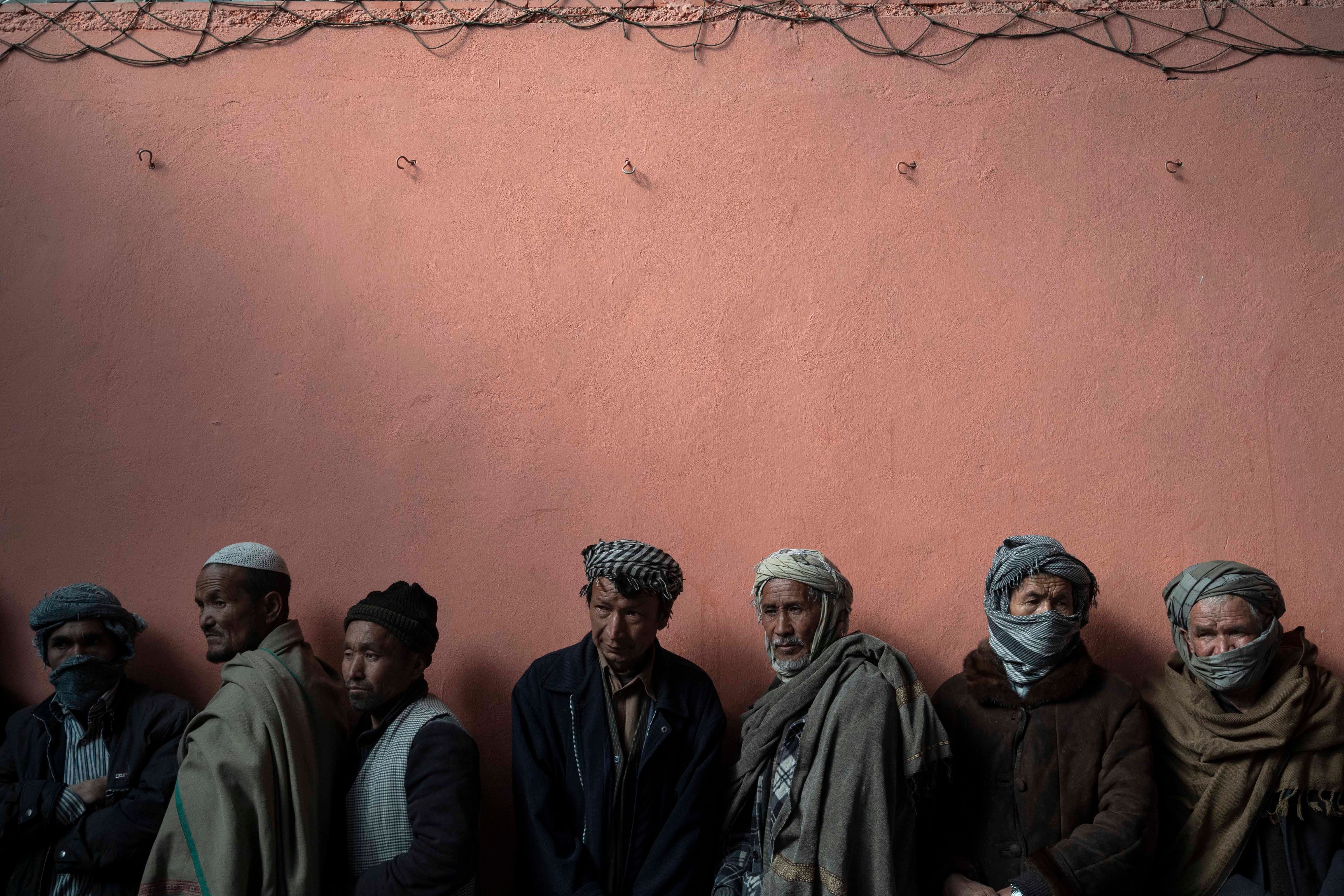 Men wait in a line to receive cash at a money distribution organized by the World Food Program in Kabul, Afghanistan, November 3, 2021. 