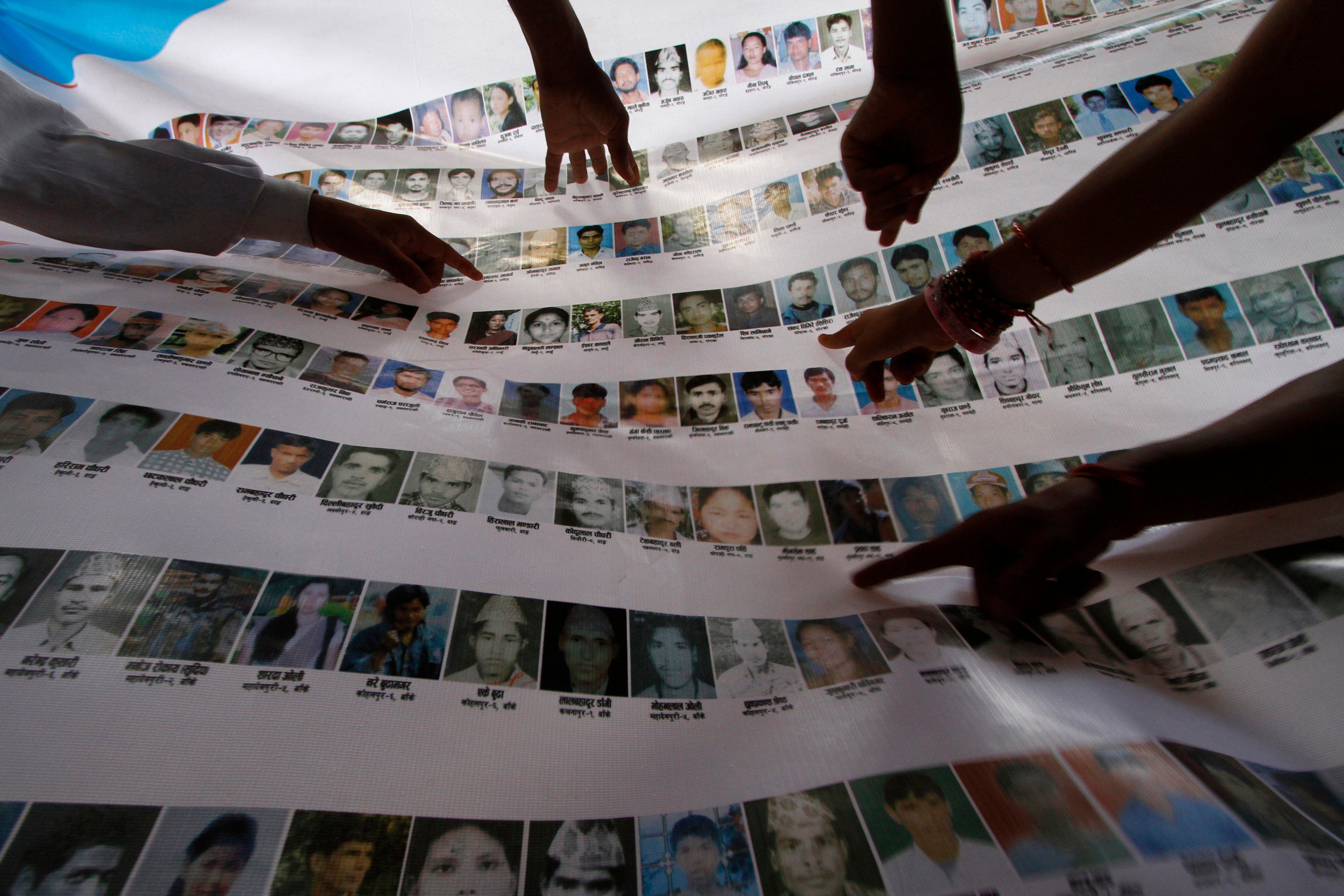 Nepalese human rights activists and relatives point to photographs of disappeared persons at an event to mark the International Day of the Disappeared, in Kathmandu, August 30, 2011. 