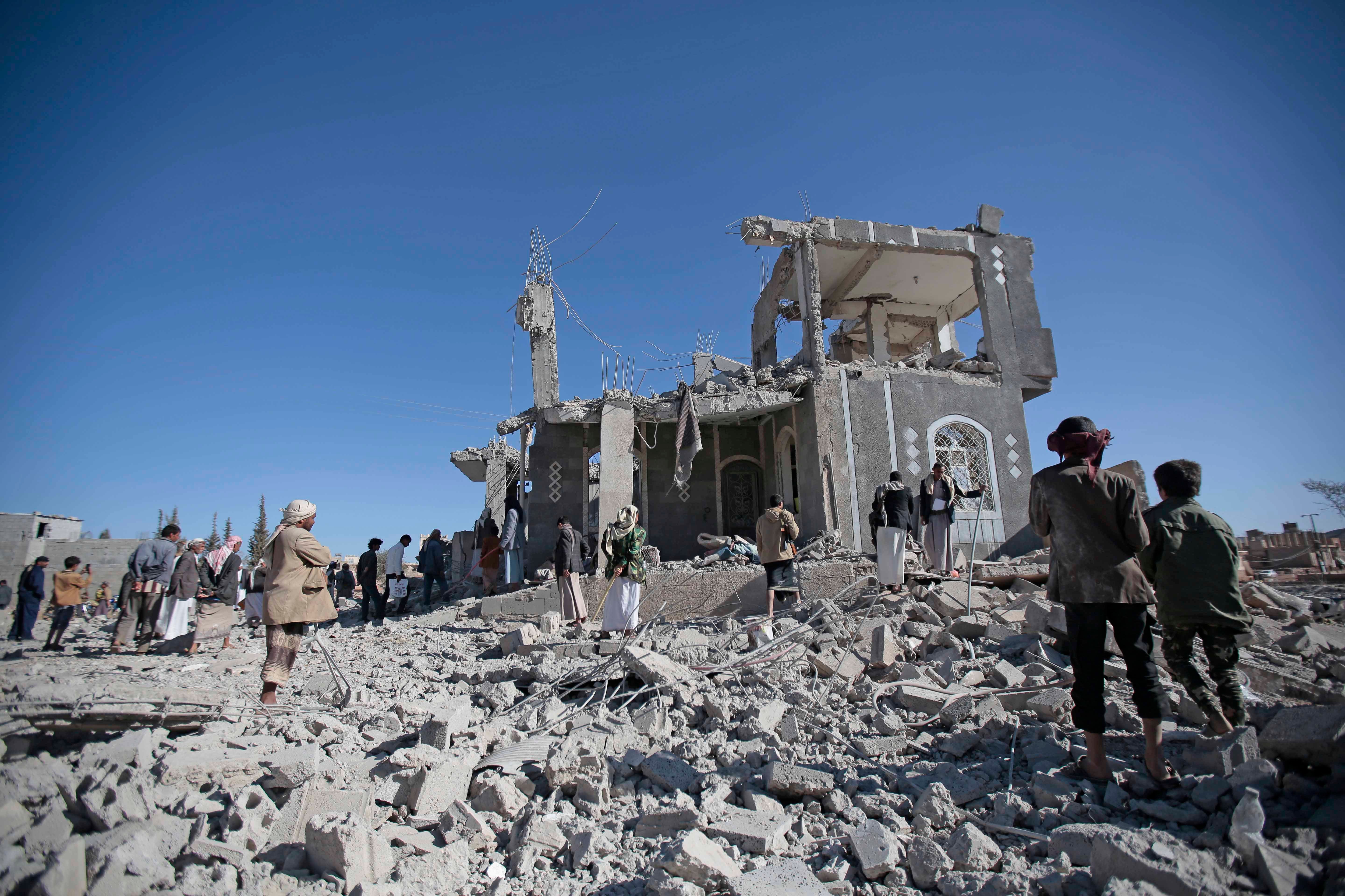 People stand in front of a damaged buildingرجال يمنيون يتفقدون منزلا مدمرا زُعِم أنه استُهدِف بغارات جوية شنتها السعودية في صنعاء، اليمن، 8 مارس/آذار 2018. 