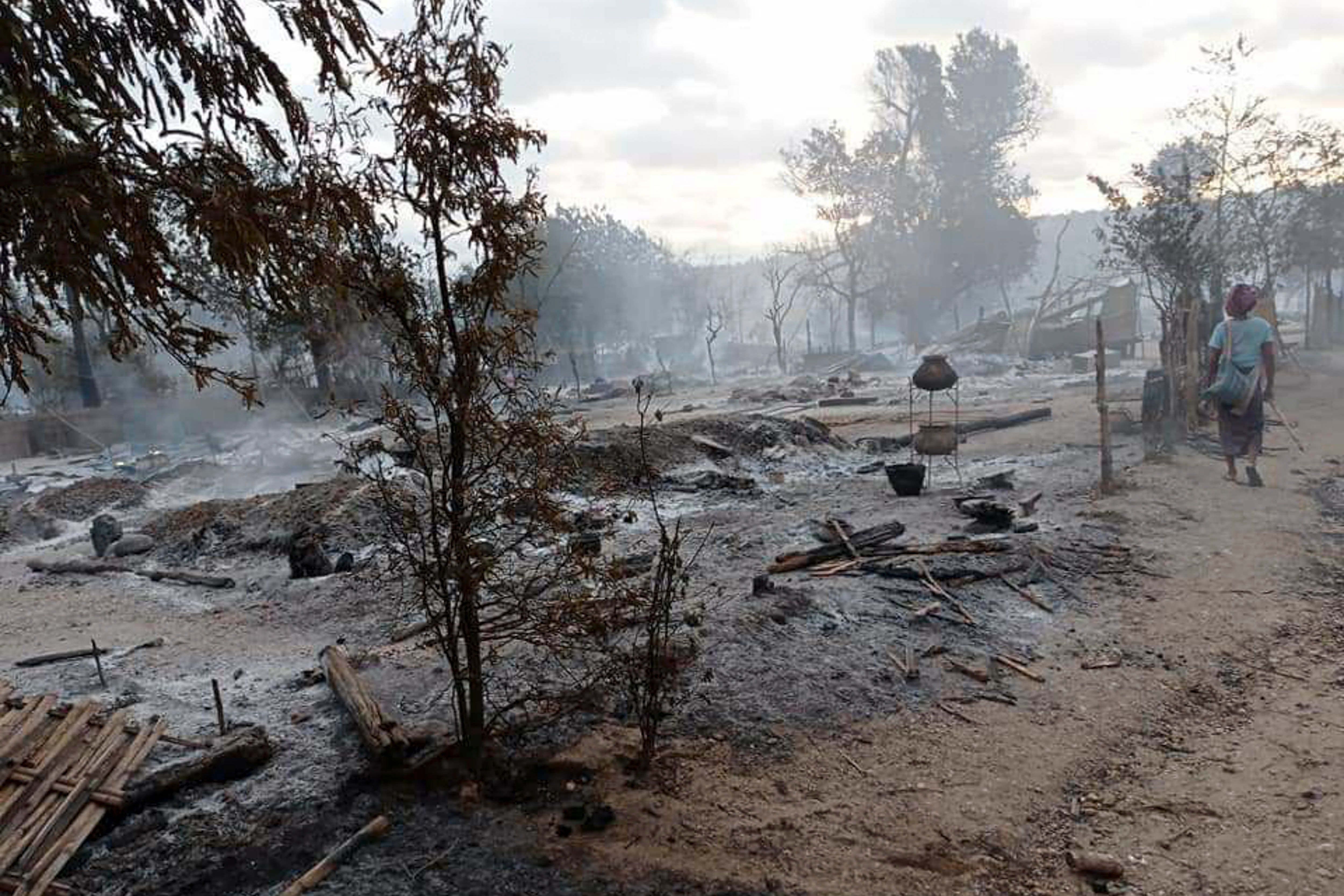 A person walks by a destroyed village