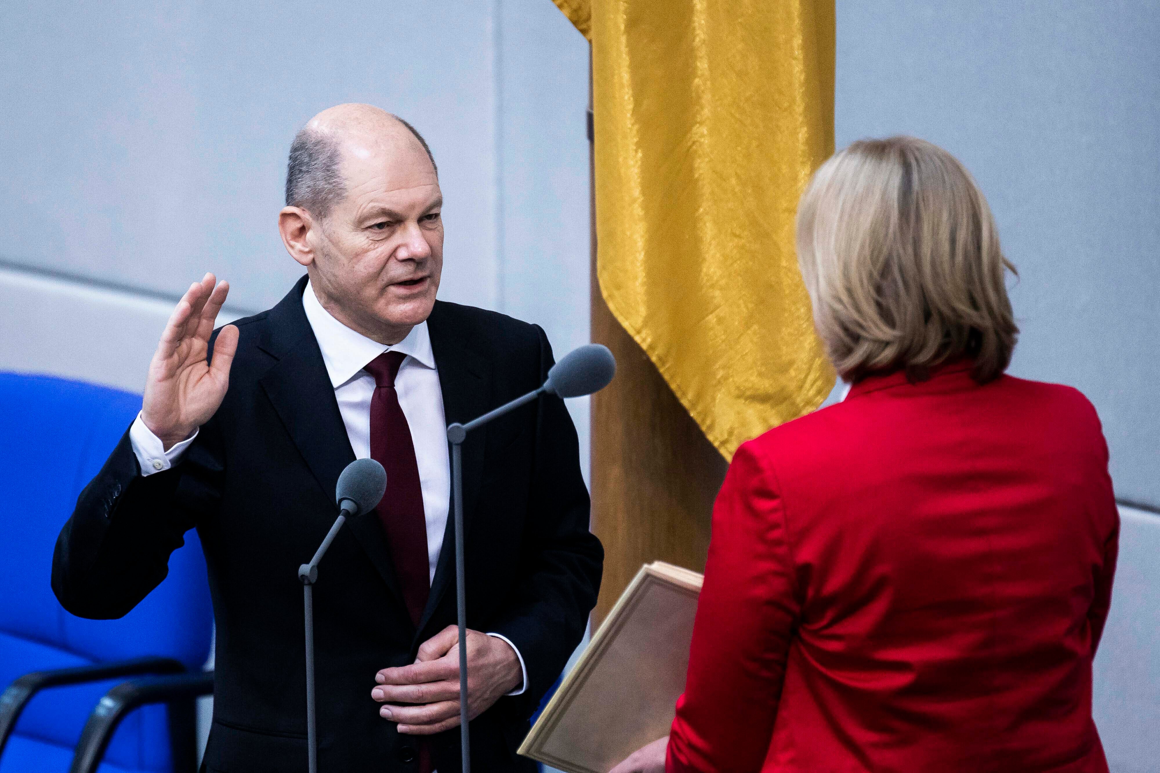 A man wearing a suit raises his right hand