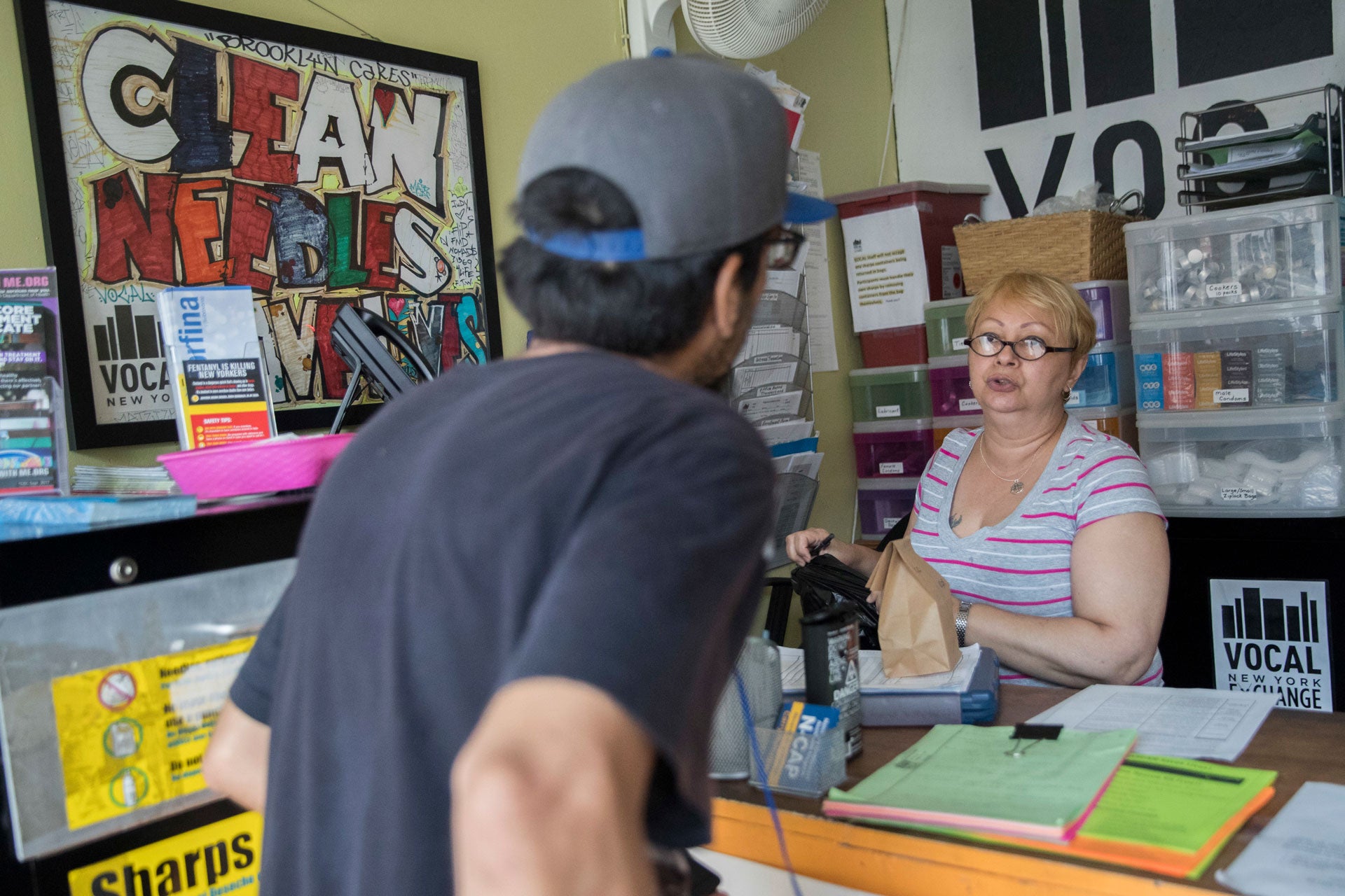 Evelyn Milan, right, prepares a package with sterile injecting equipment for a member at VOCAL-NY's headquarters in the Brooklyn borough of New York, June 3, 2018. 