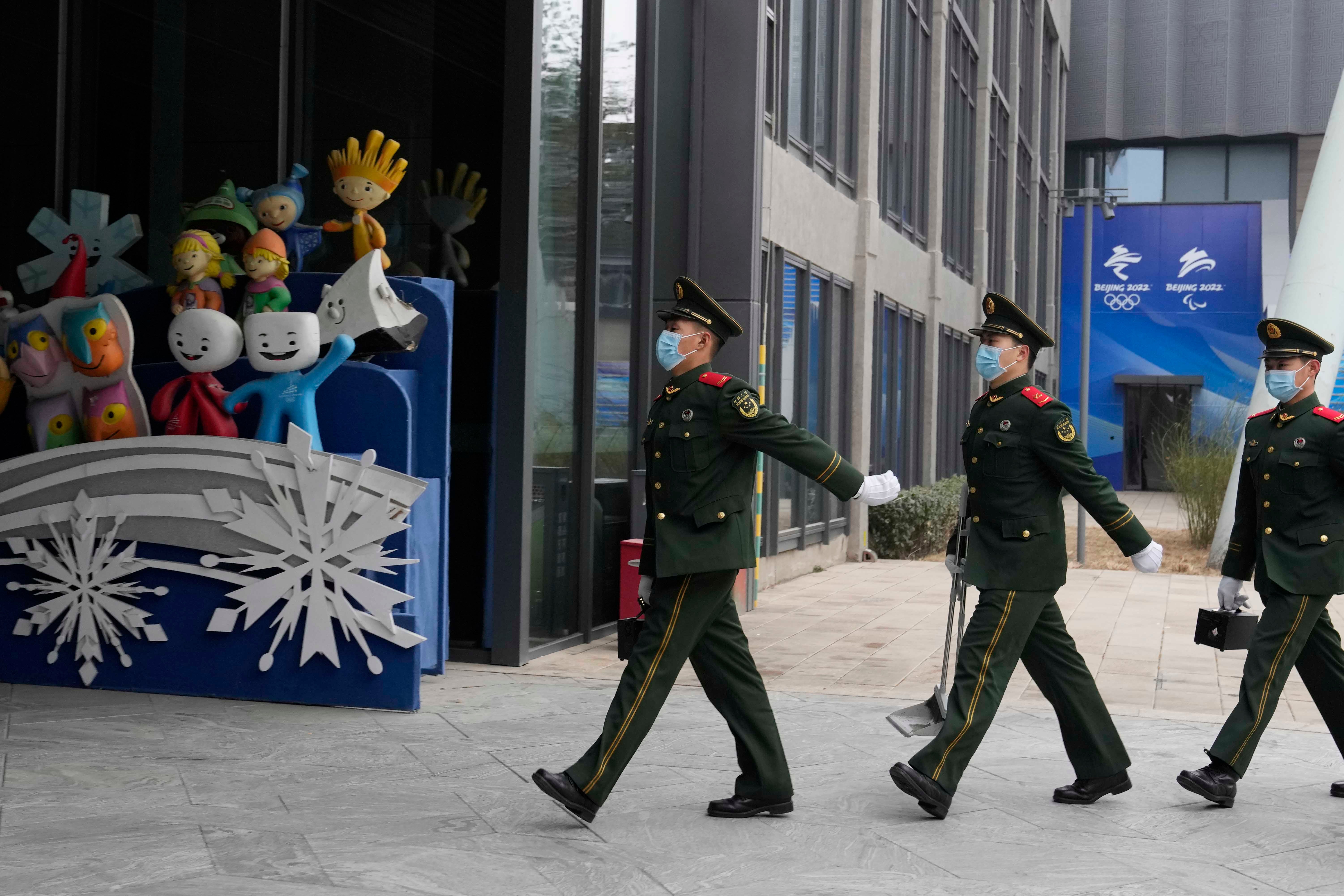 數名武警列隊行經首鋼遺址公園內的冬季奧運會吉祥物，中國北京，2022年1月21日。© 2022 AP Photo/Ng Han Guan