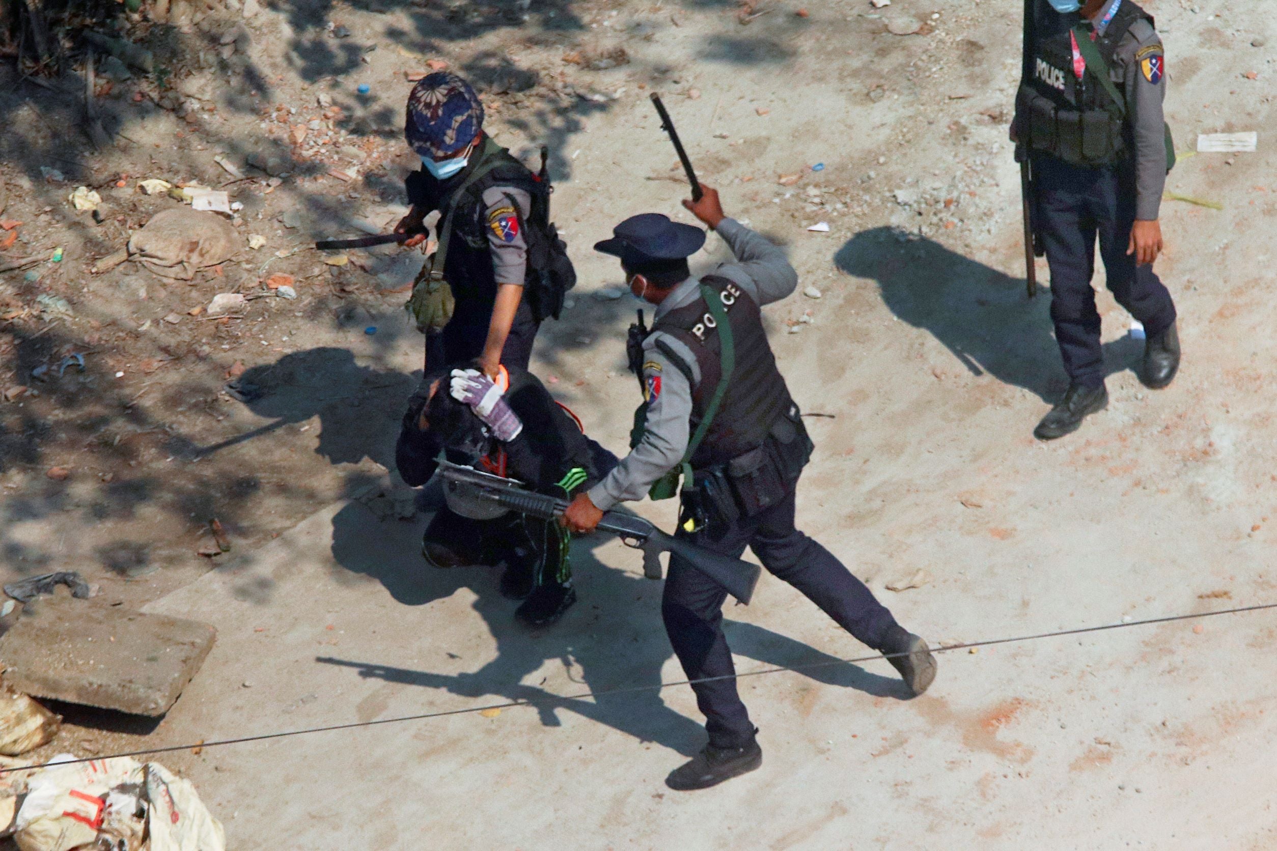 Un policier levait son bâton au-dessus de la tête d’un homme accroupi lors de la répression d’une manifestation à Yangon (Rangoun), le 6 mars 2021.