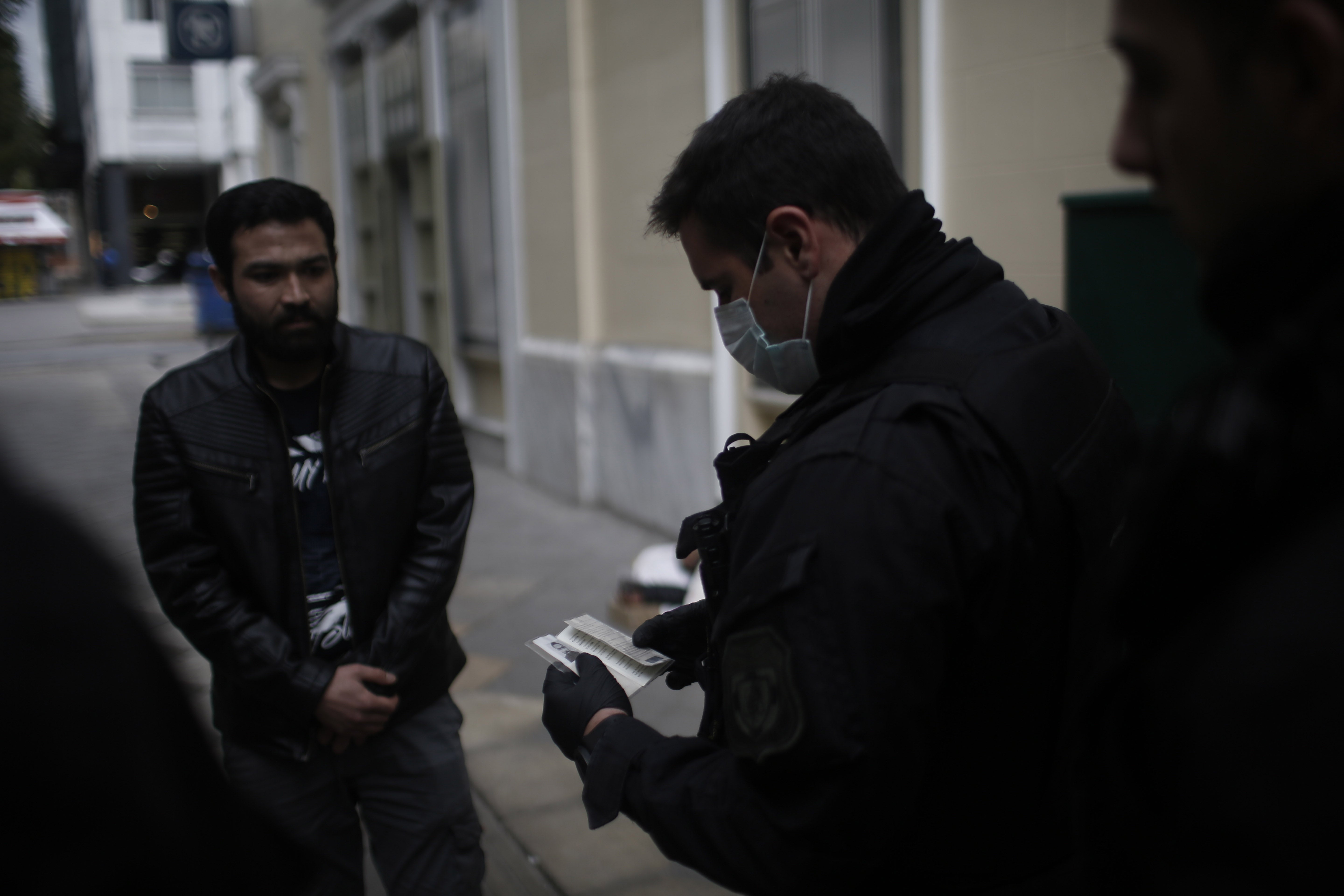 Police officers check the documents and permissions of people in the streets of Athens, Greece, March 23, 2020. 