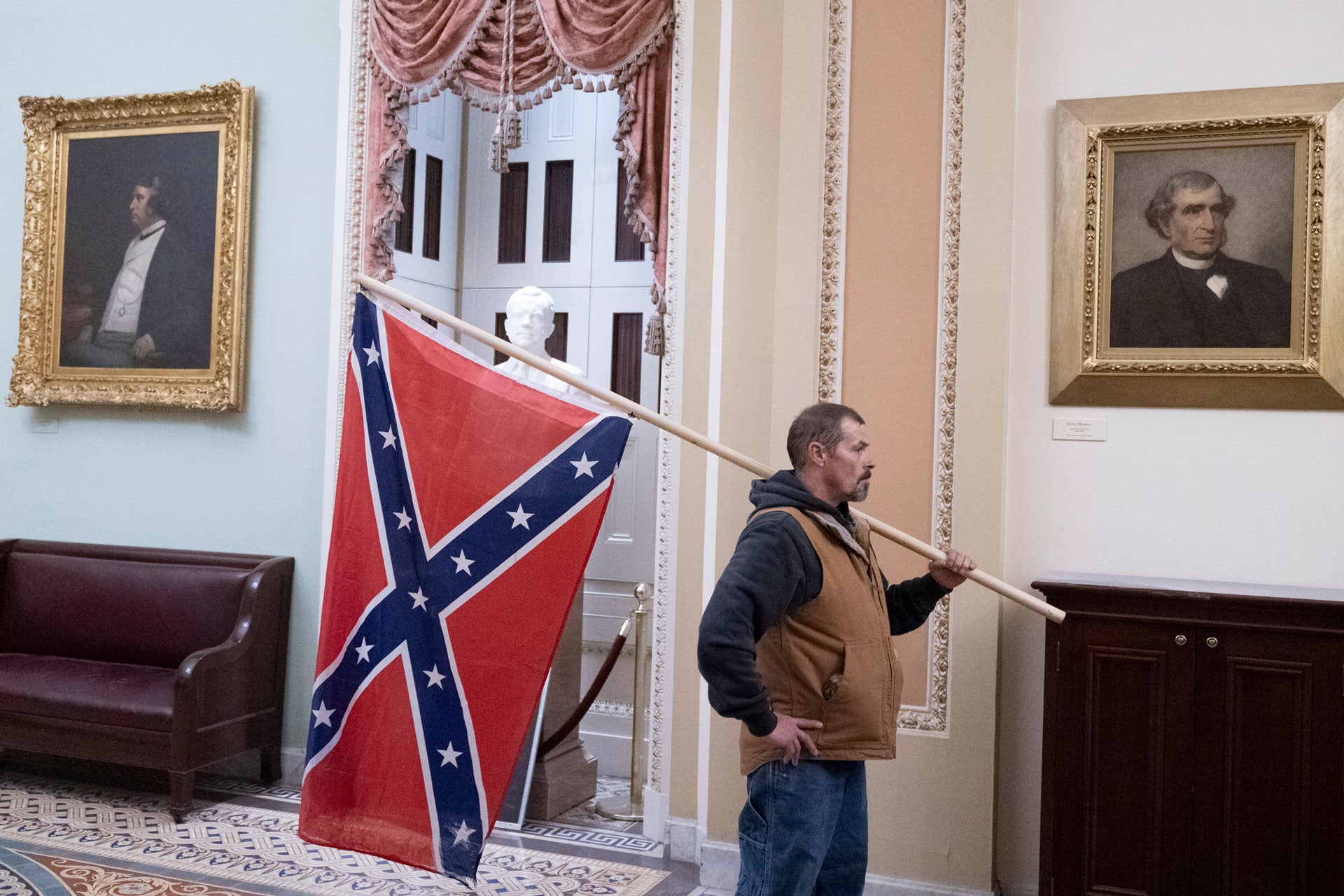 A protester stands with a Confederate flag after storming the Capitol during a Joint Session of Congress in which members were to certify the 2020 Presidential election on January 6, 2021.