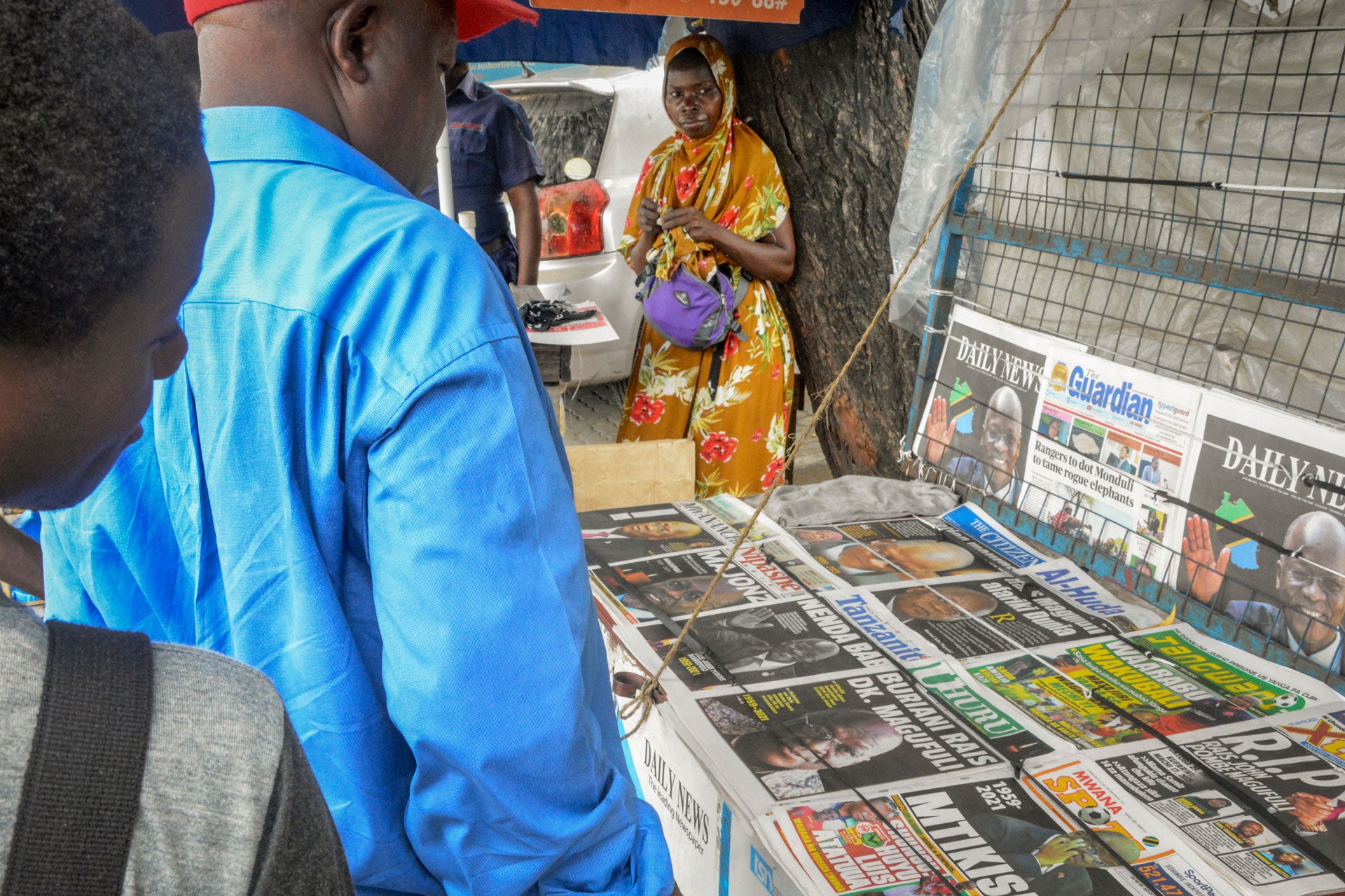 People stop to read front pages at a newspaper stand on a street in Dar es Salaam, Tanzania, March 18, 2021.