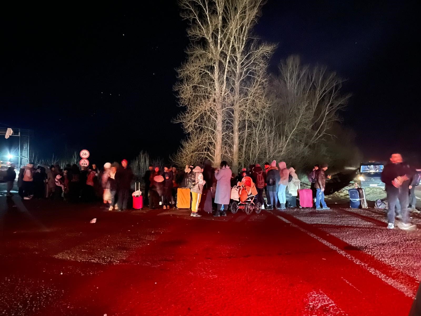 Des Ukrainiens regroupés à Rava-Ruska, dans l’ouest de l’Ukraine, attendaient avant de pouvoir franchir la frontière avec la Pologne, dans la nuit du 25 février 2022. Les lueurs rougeâtres provenaient d’un feu de camp qui avait été allumé pour réchauffer le groupe.