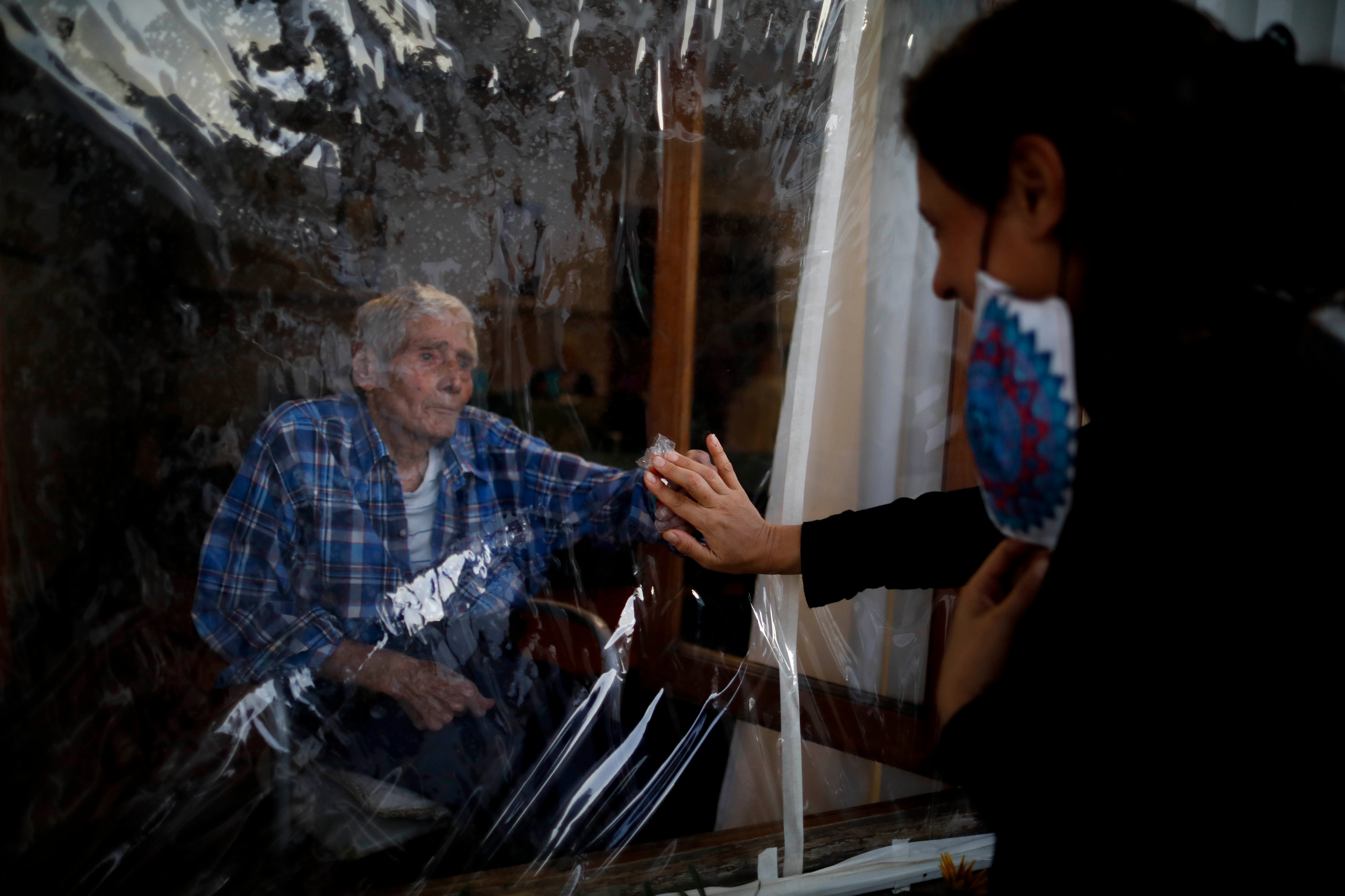 A man and woman touch hands through a plastic sheet