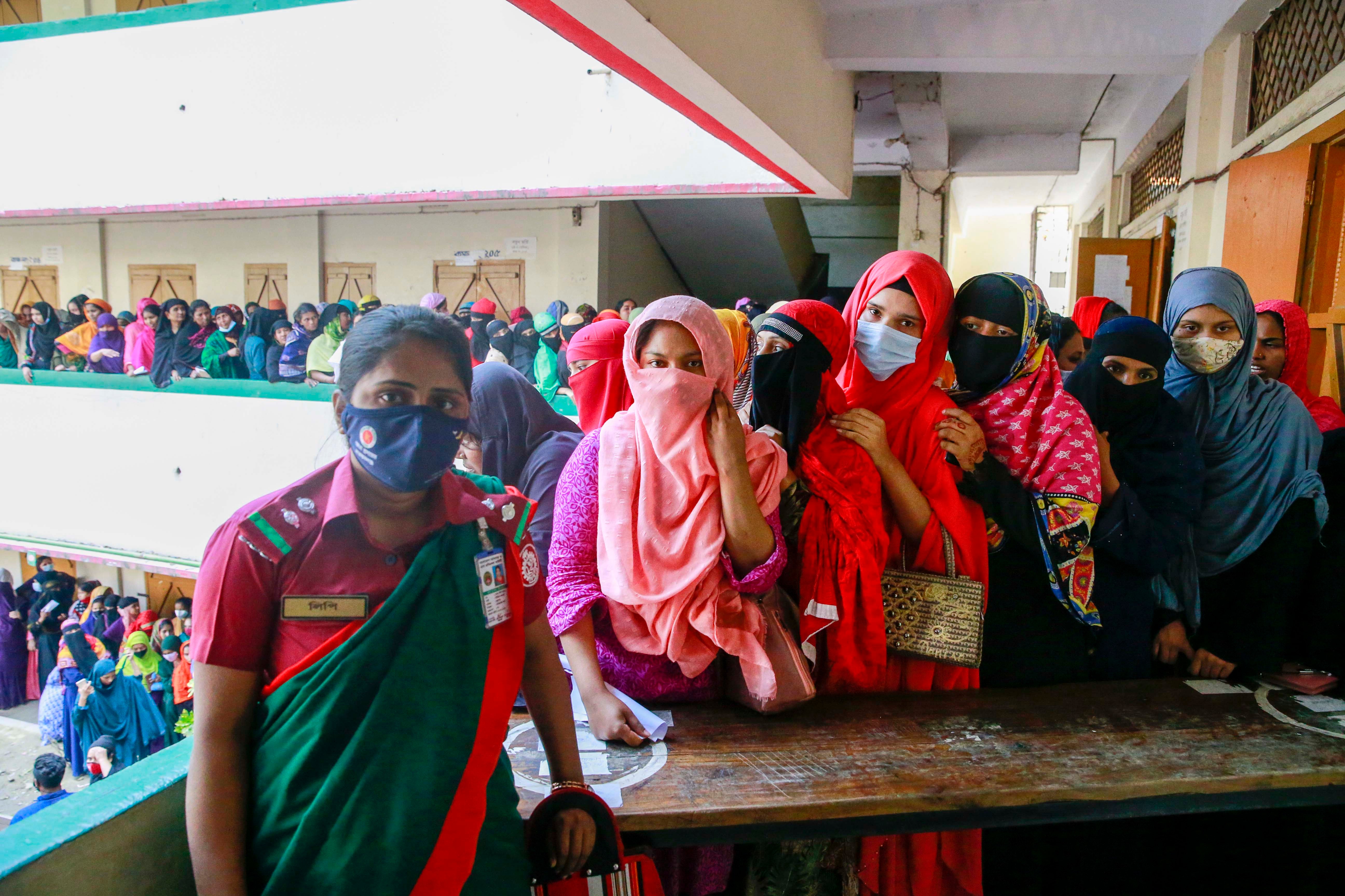 Women in protective face masks stand in a long line