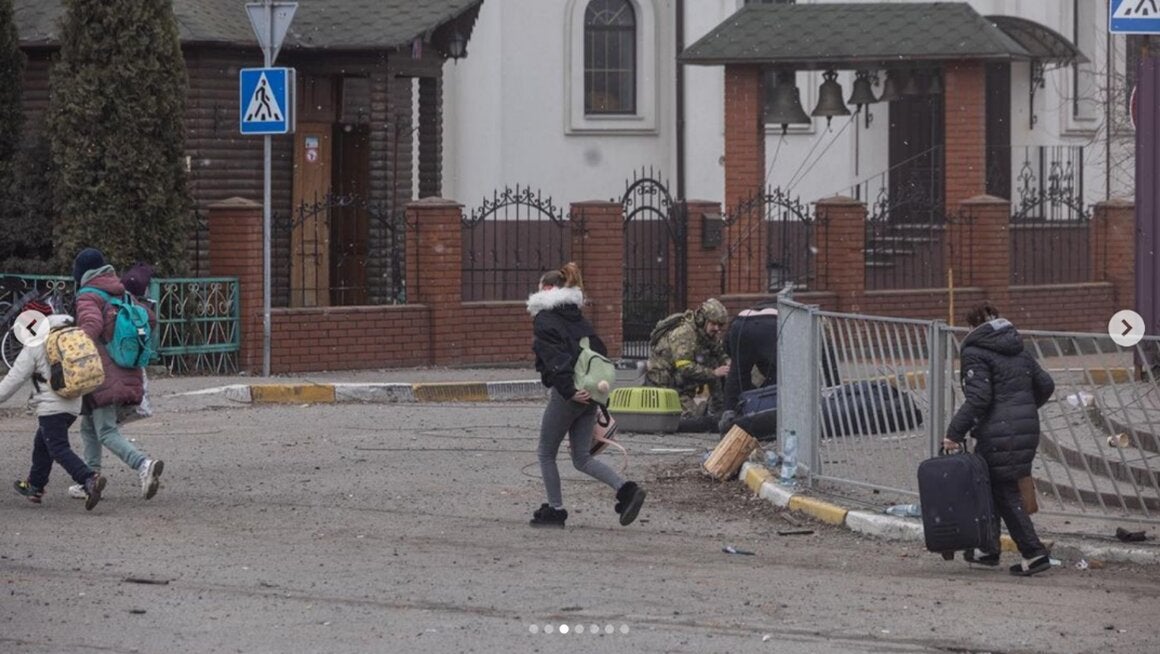 Un membre de forces de sécurité ukrainiennes s’agenouillait (à l’arrière-plan de la photo) près de civils blessés et tués par l’explosion d’un projectile tiré par les forces russes à Irpin, dans le nord de l’Ukraine, le 6 mars 2022. 