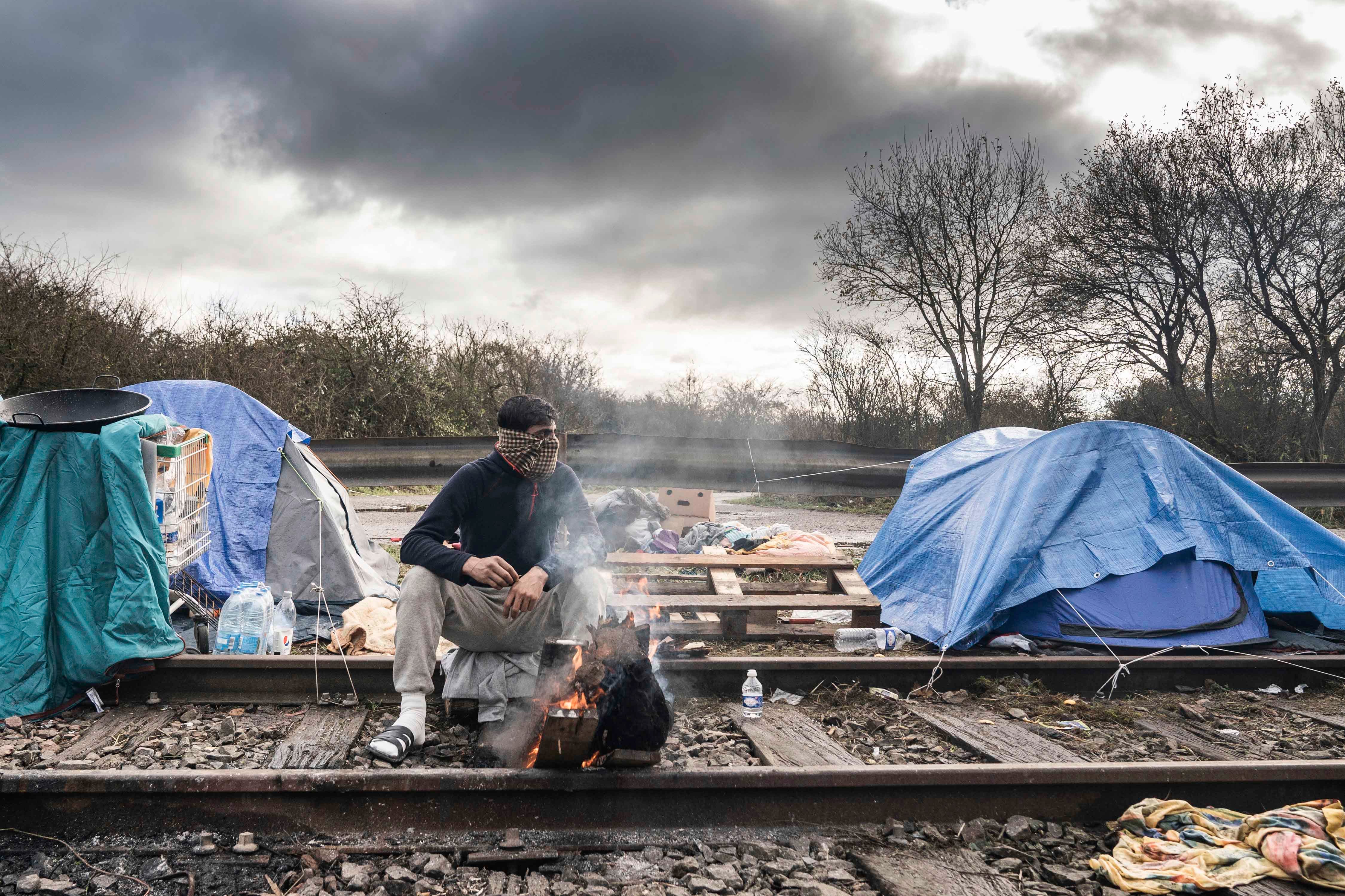 Un migrant se réchauffe en brûlant du bois de chauffage dans un camp de migrants improvisé dans la région de Dunkerque, dans le nord de la France